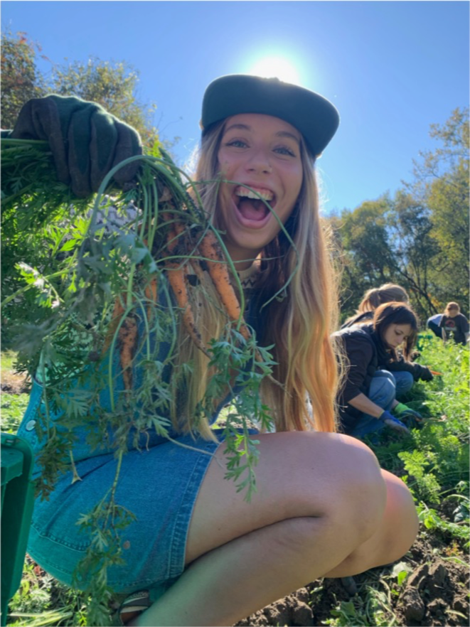Intern Aria Wetzel smiling and holding carrots