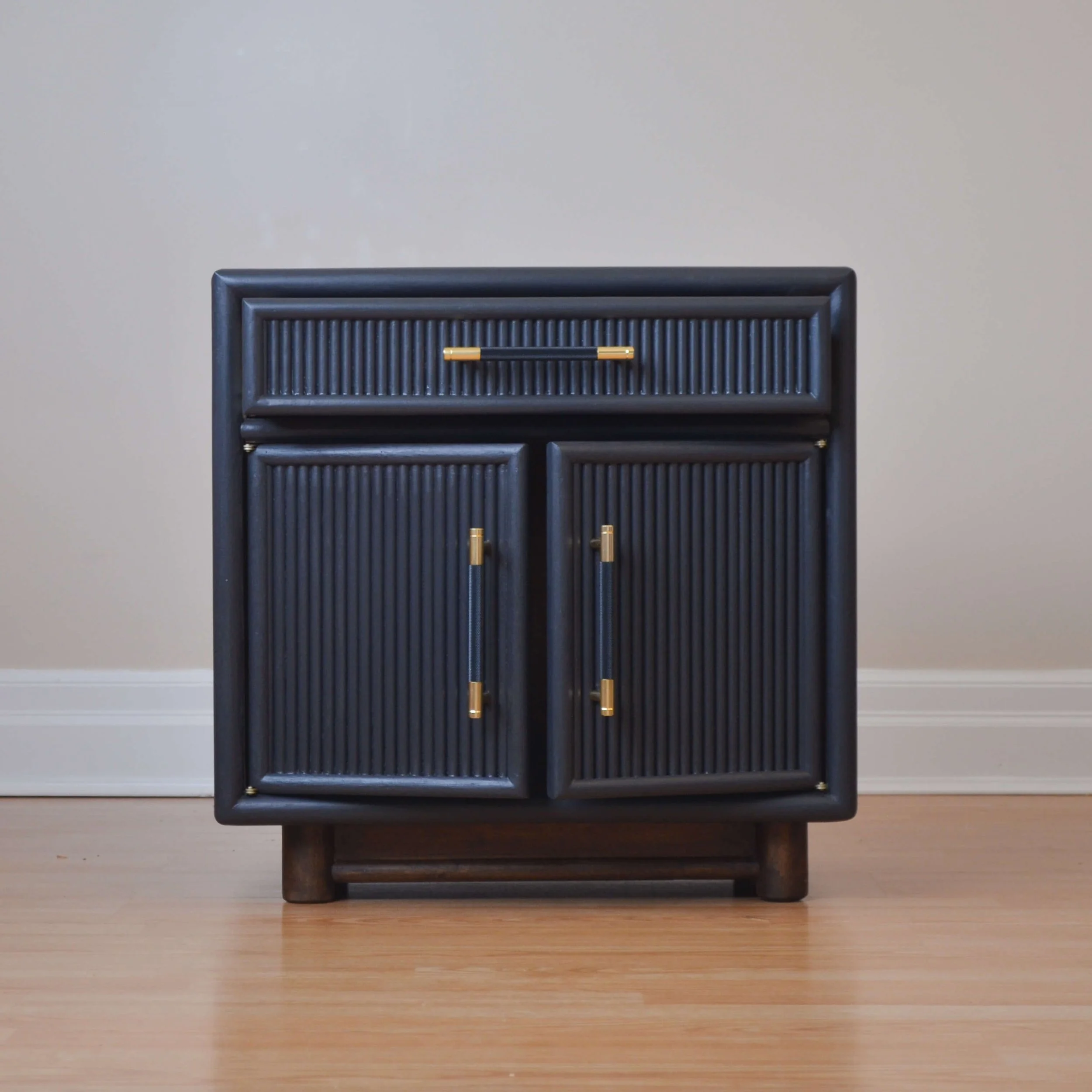 Refinished set of 2 modern reeded nightstands in matte black with gold and black handles, featuring a rounded leg base.