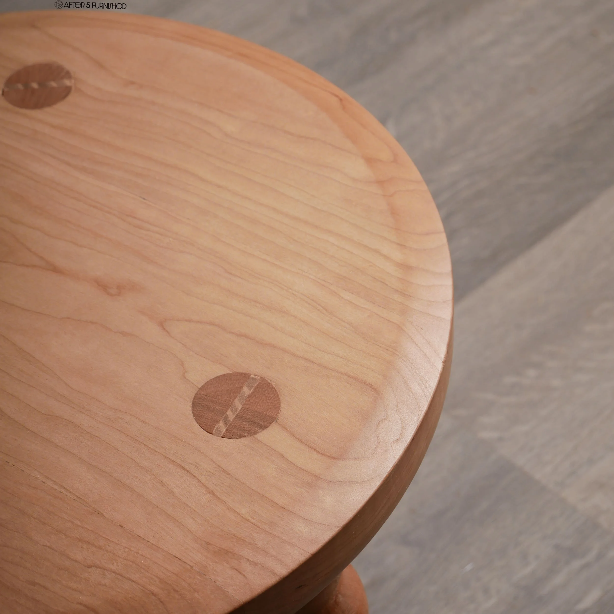 Close-up of cherry wood grain on handcrafted stool with traditional wood joinery