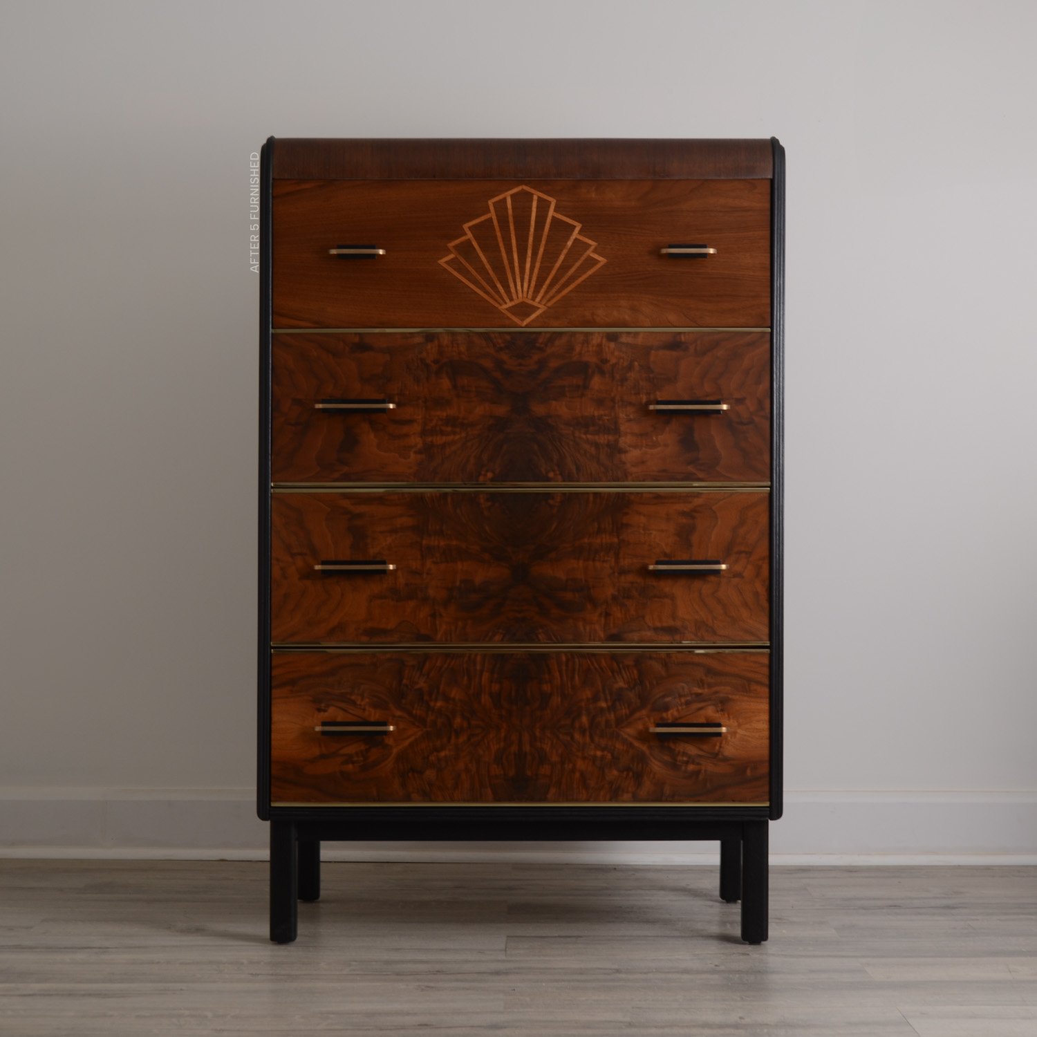 Front view of the refinished Art Deco walnut tall dresser. Features highly figured walnut veneer drawers, a Padauk wood waterfall edge, and a geometric starburst maple wood inlay on one drawer.