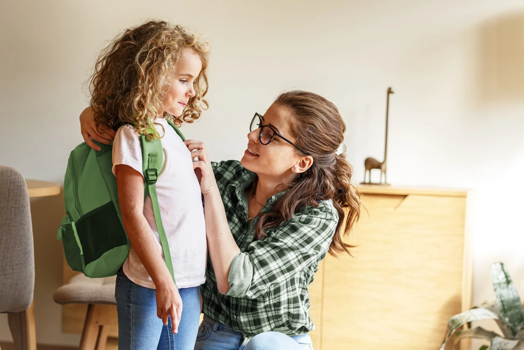 Mom putting backpack on her daughter