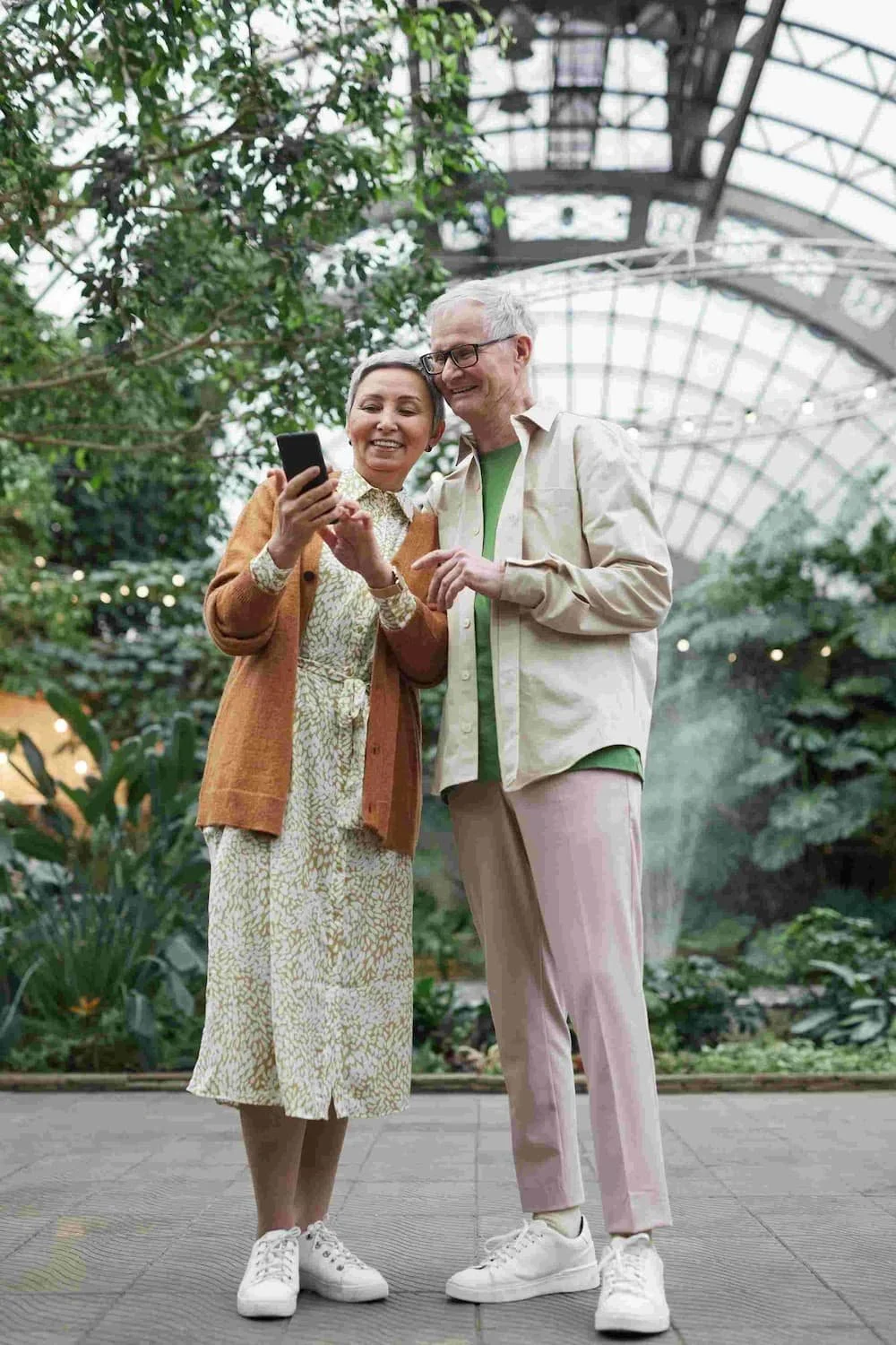 man and woman smiling at phone in botanical garden