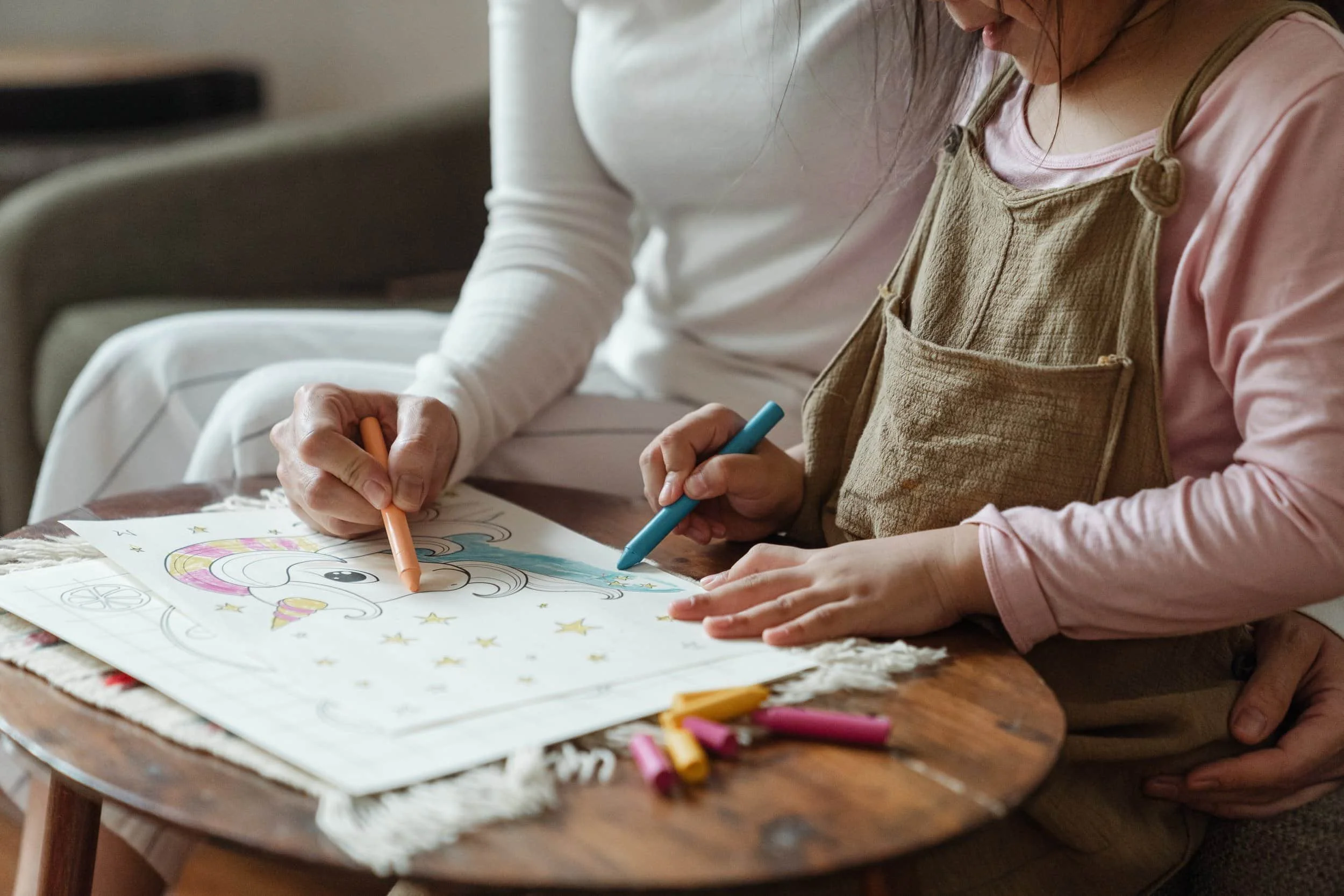 mother and daughter coloring a picture on coffee table