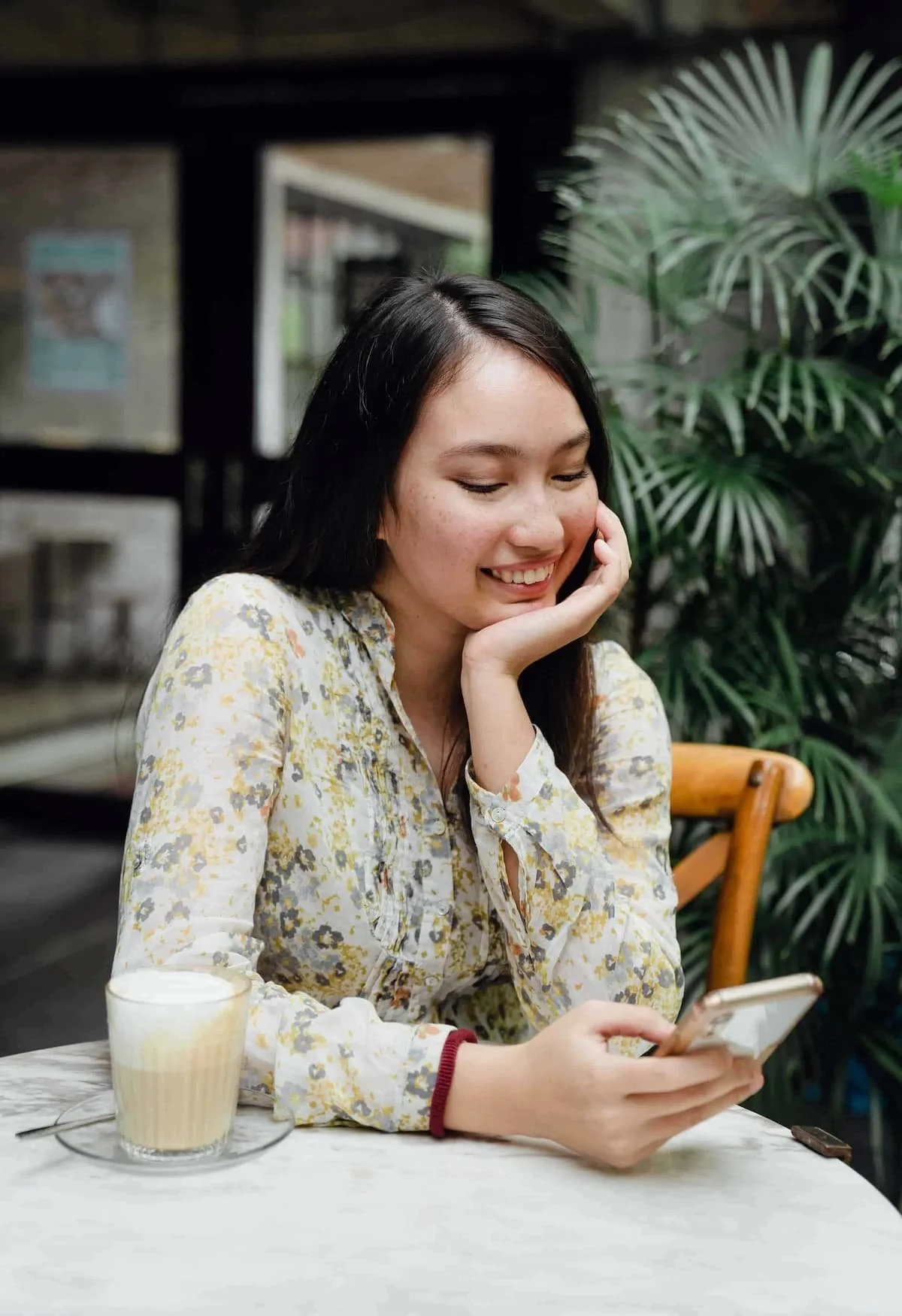 women checking her phone while drinking a coffee