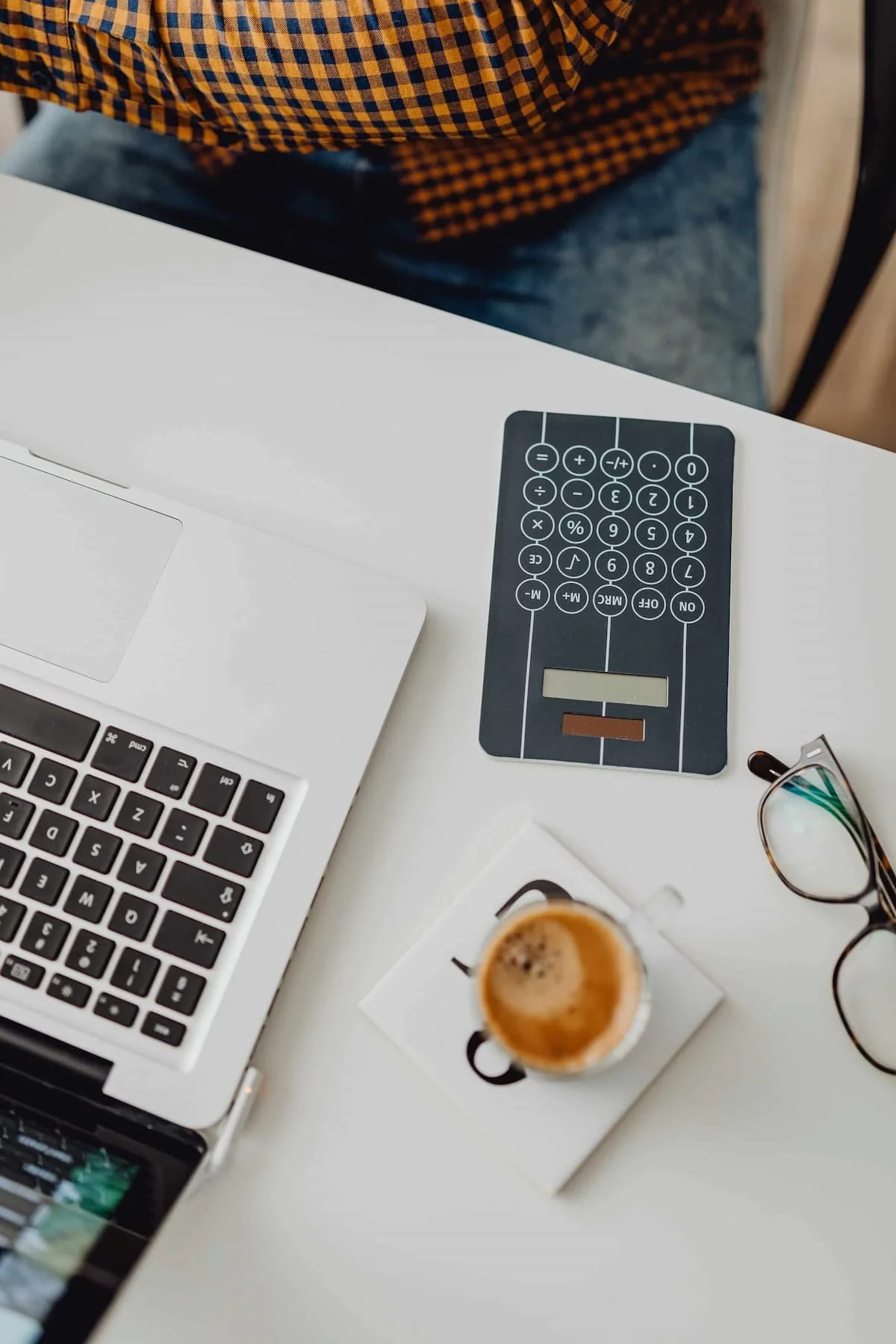 calculator and laptop on desk with coffee and eye glasses