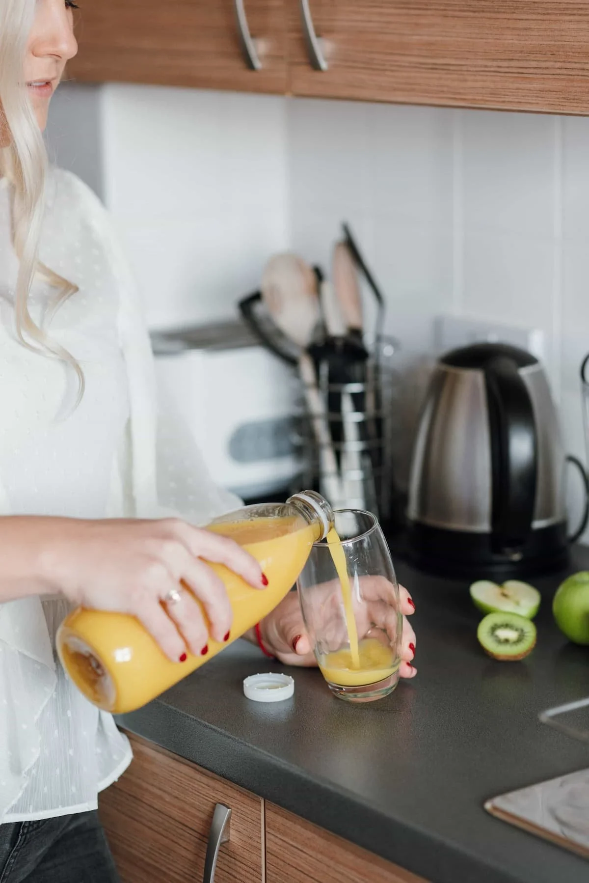 woman in kitchen pouring orange juice