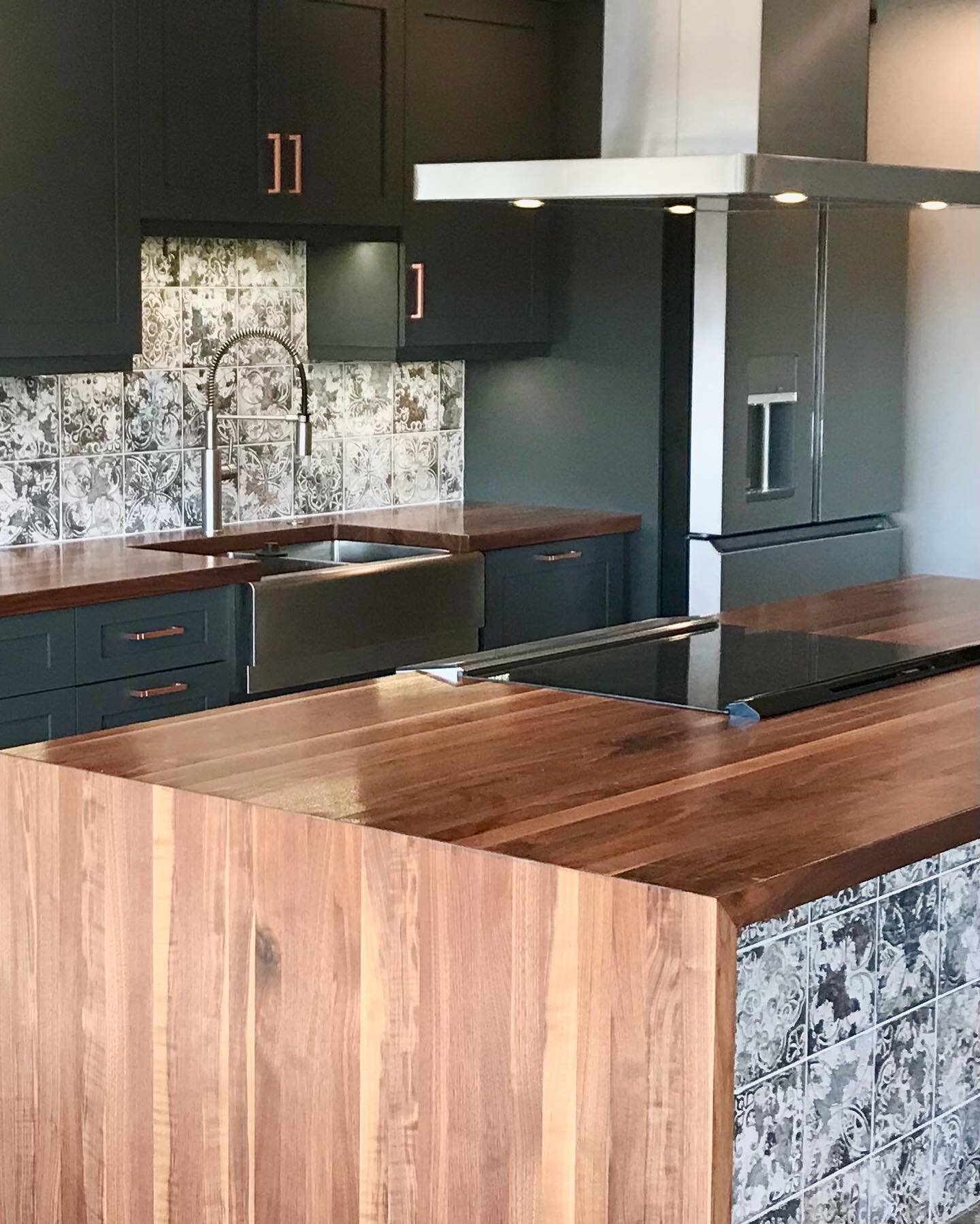 Turning this Country Club Plaza penthouse condo into an open concept floor plan took some maneuvering but the end result is stunning. This kitchen features striking graphite cabinetry, solid walnut waterfall countertops and copper accents. The graphi