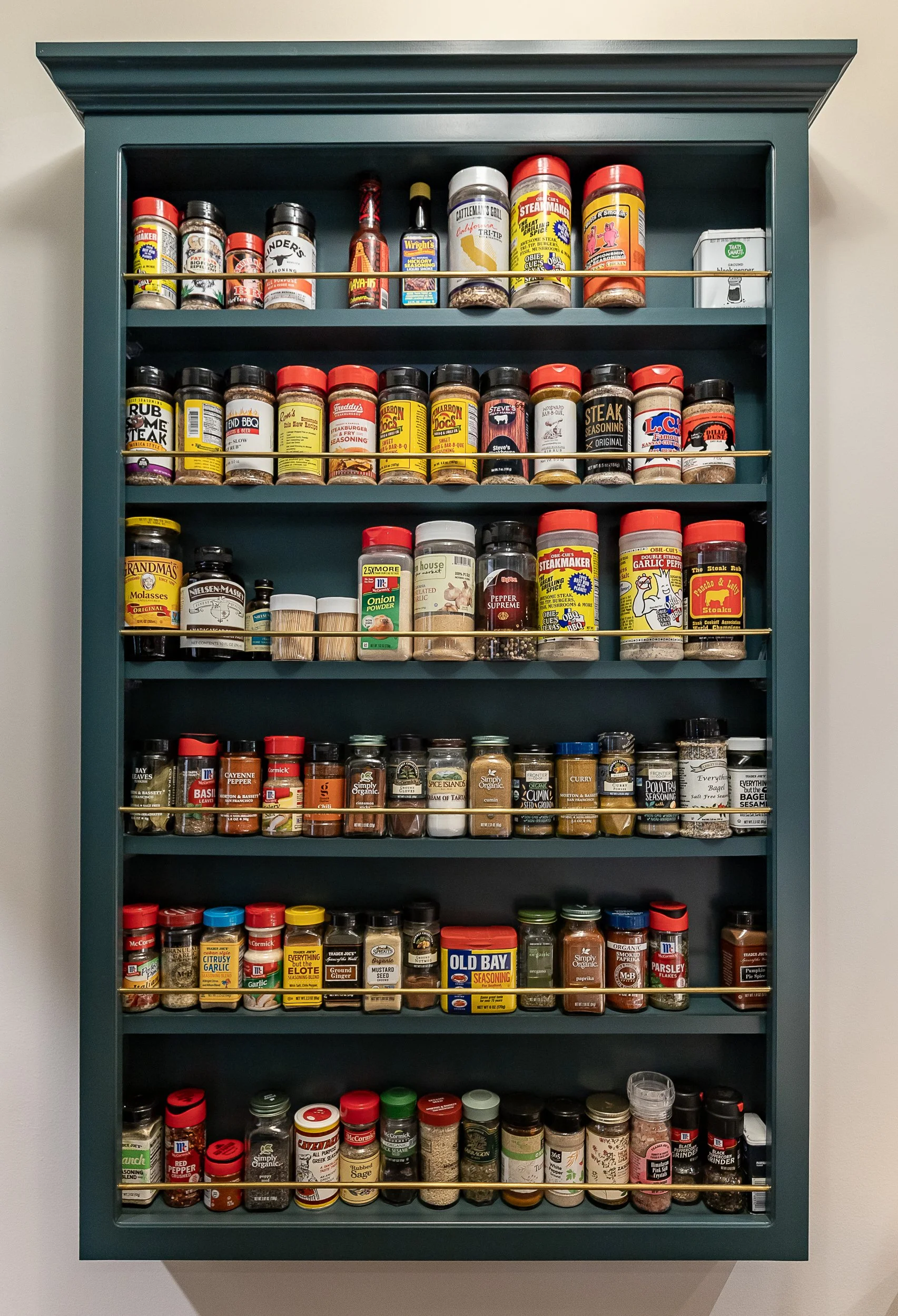 Blue spice rack filled with various containers of herbs, spices, and seasonings, organized on multiple shelves.