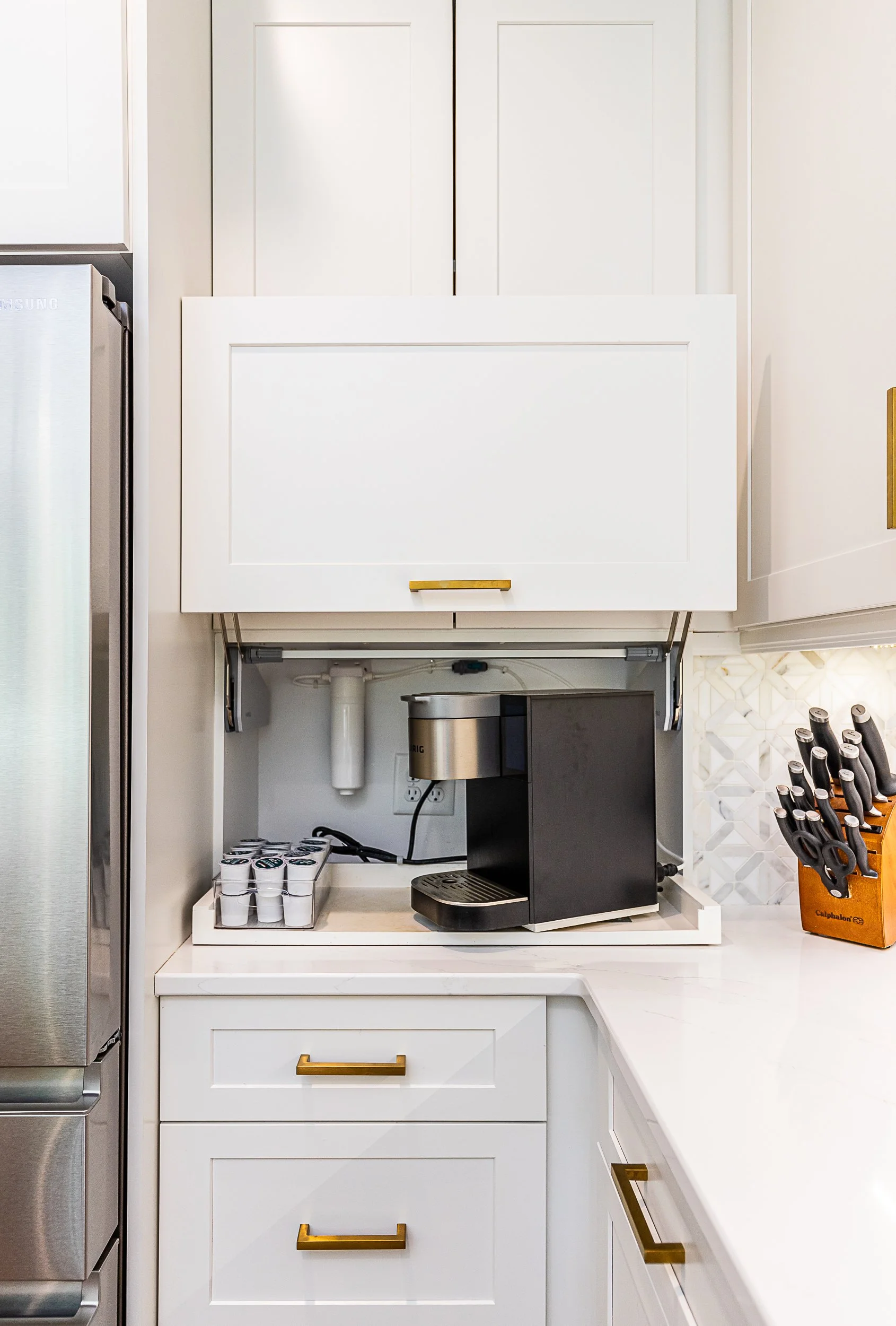 A kitchen countertop with a black coffee maker, a pack of coffee pods, and a knife set on the right.