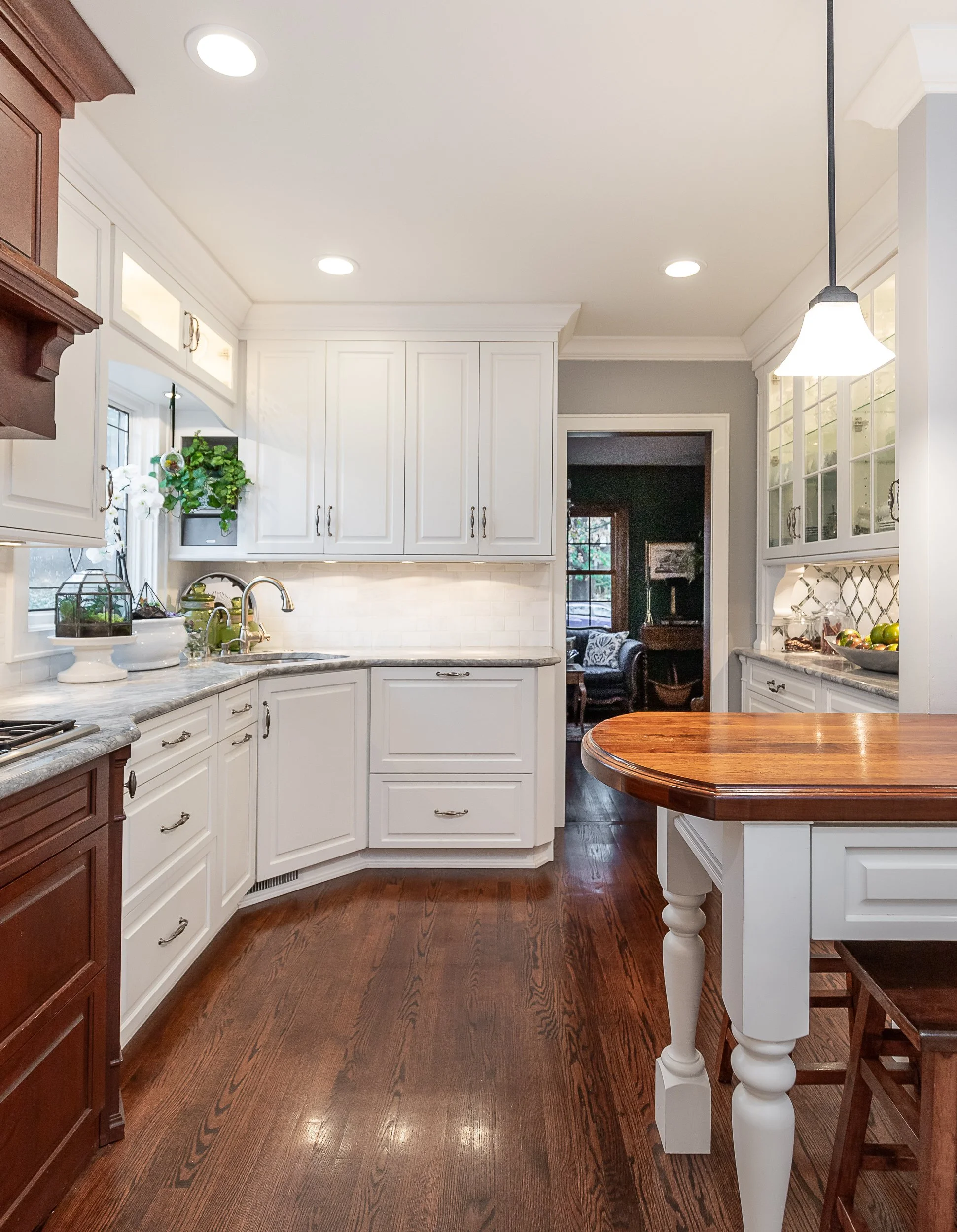 A kitchen with white cabinets, a quartz countertop, and a wooden table with chairs.