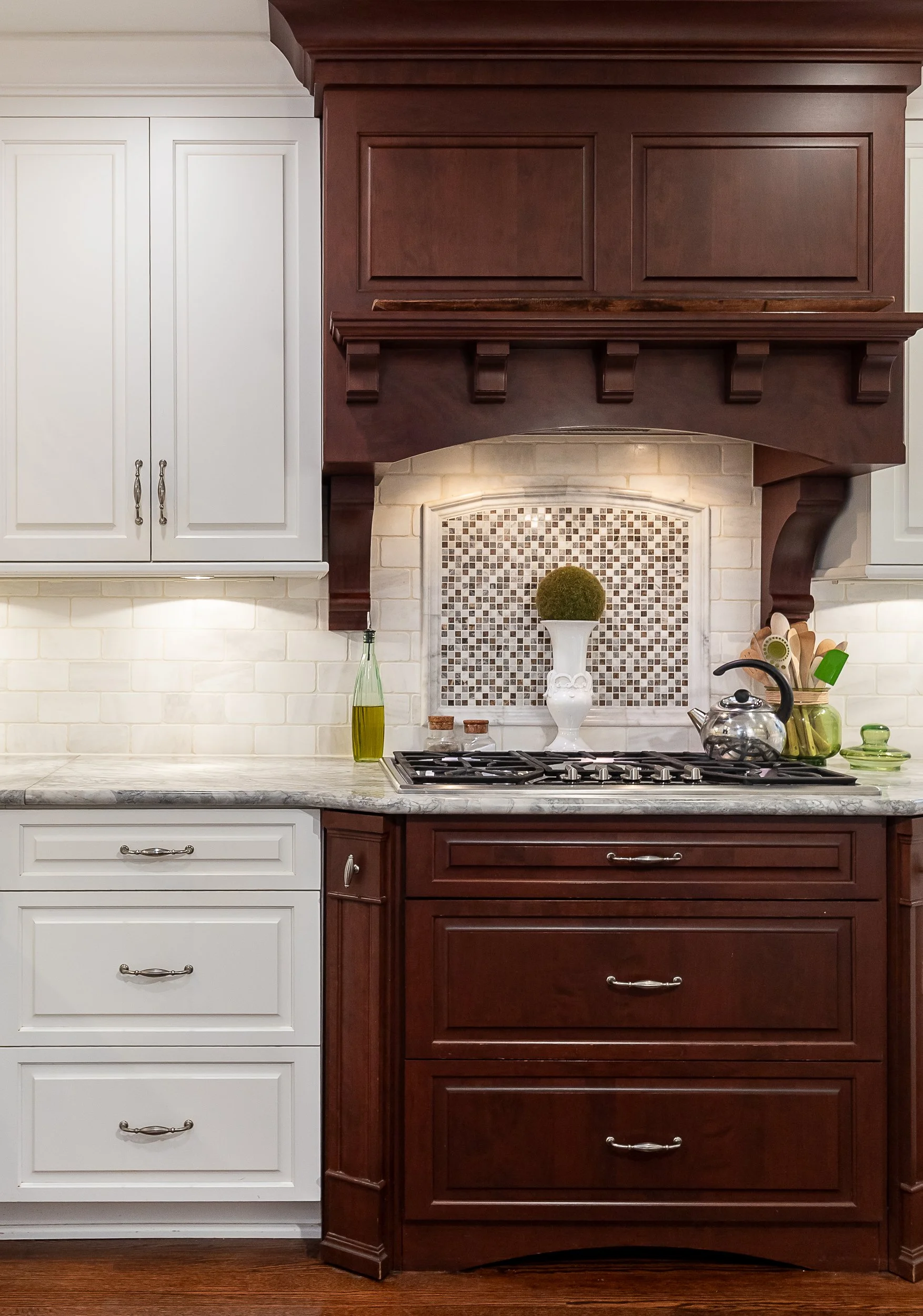 Kitchen with white and brown cabinets, a quartz countertop, a small mosaic backsplash, and kitchen utensils including a teapot and decorative items.