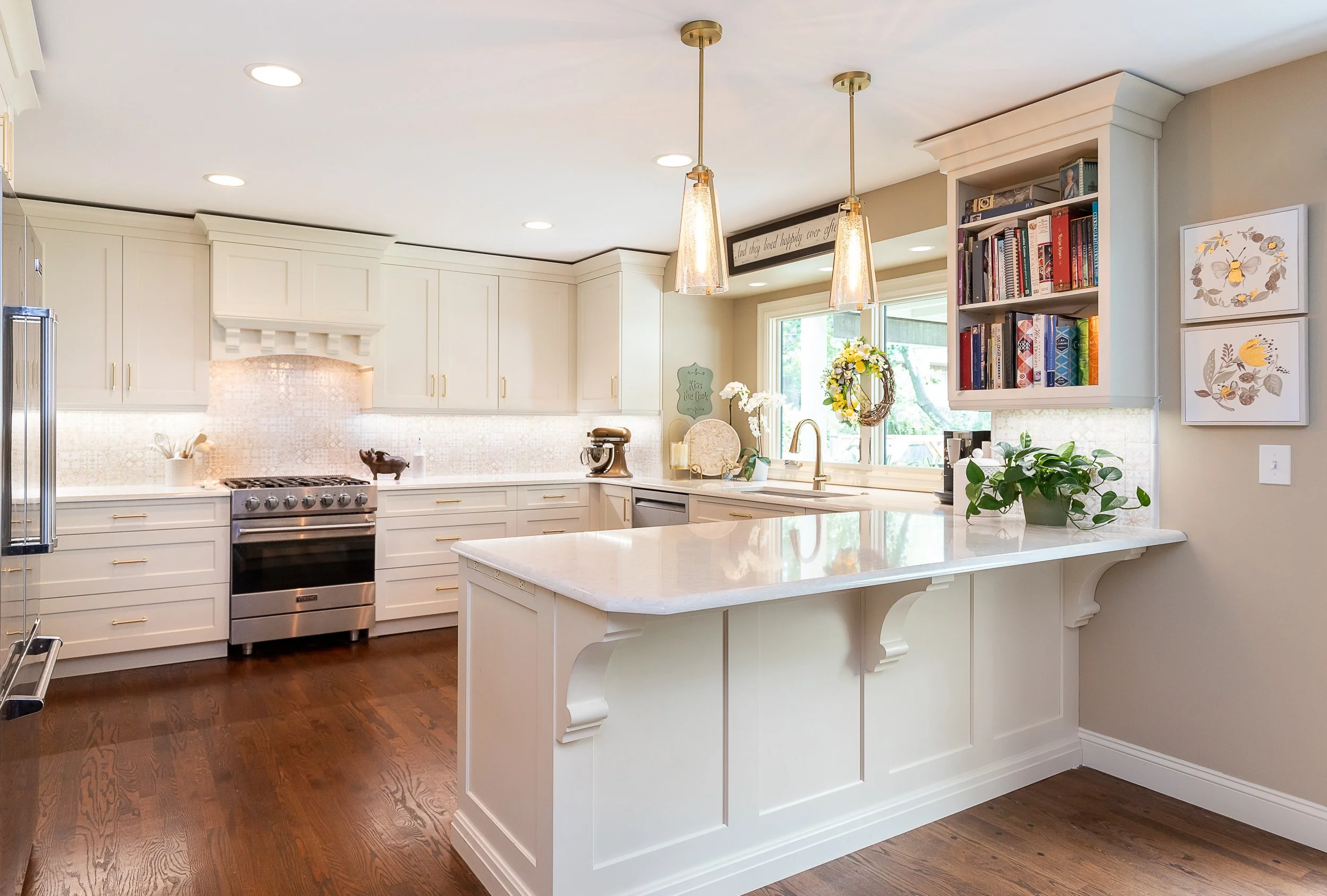 Bright kitchen with beige cabinets, quartz countertop island, and wooden flooring, decorated with plants, books, and kitchen accessories.