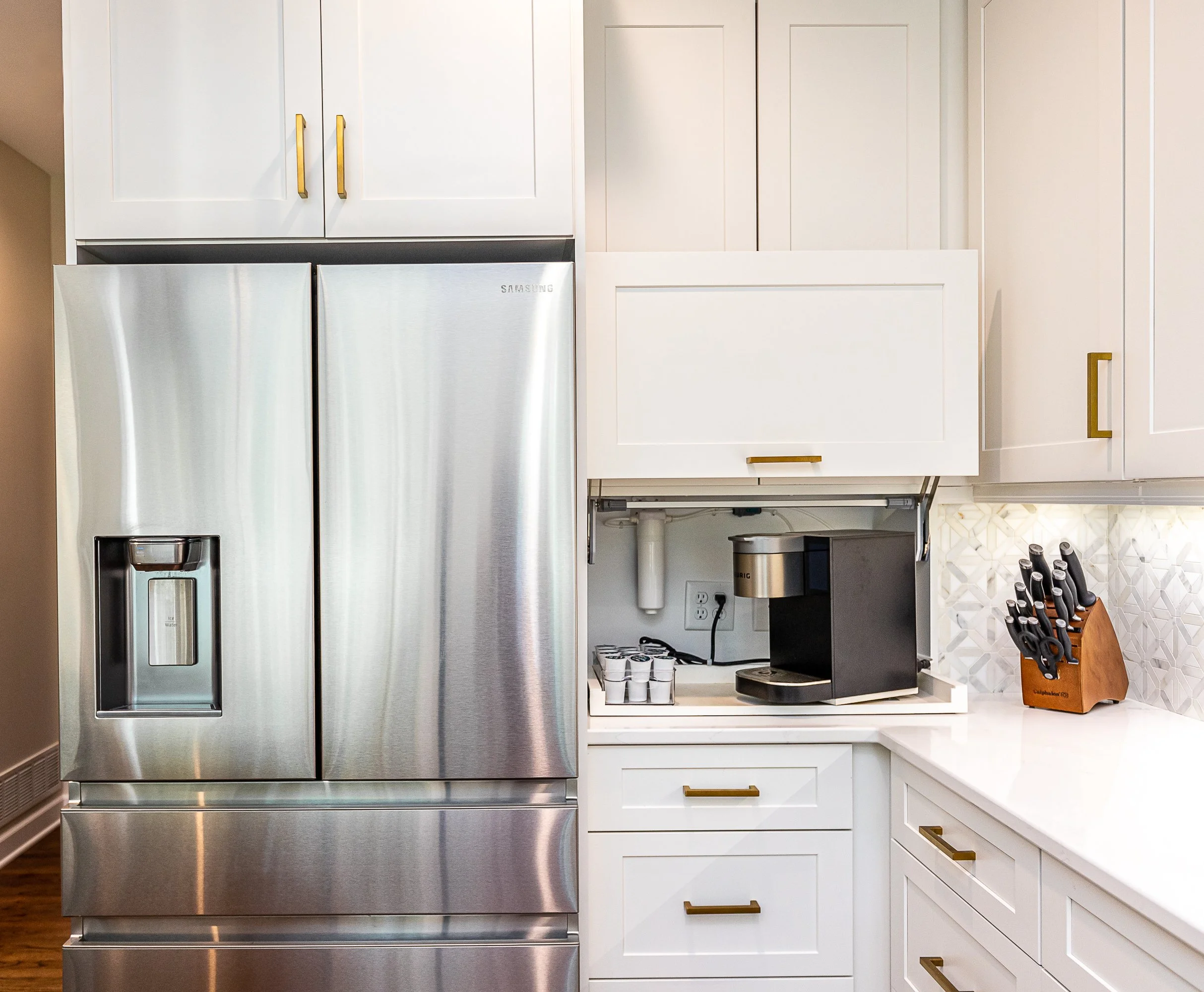 Kitchen with white cabinets, stainless steel refrigerator, coffee maker, and a knife block on the countertop.