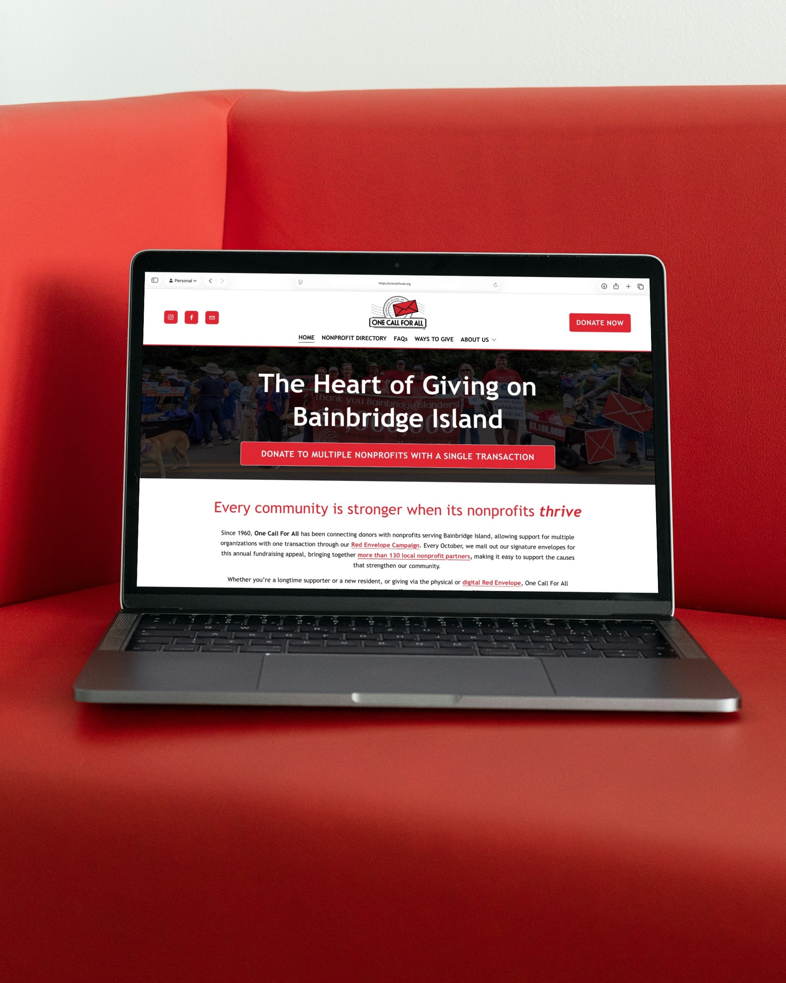 Laptop displaying the homepage of a nonprofit organization called One Call For All on a red couch with a white wall in the background.