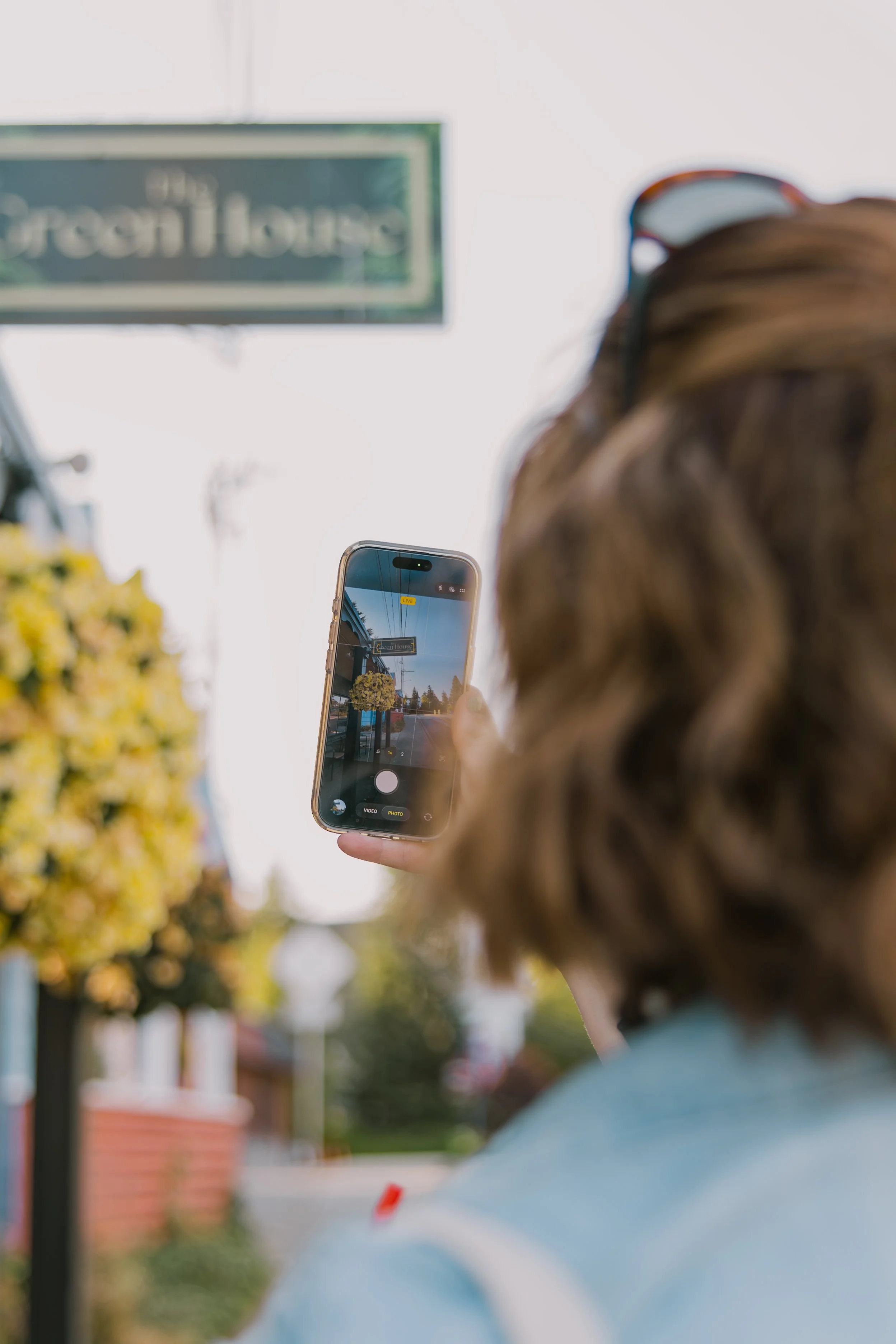 Person sitting by a window on a rainy day, taking a photo of the rain outside with a smartphone.