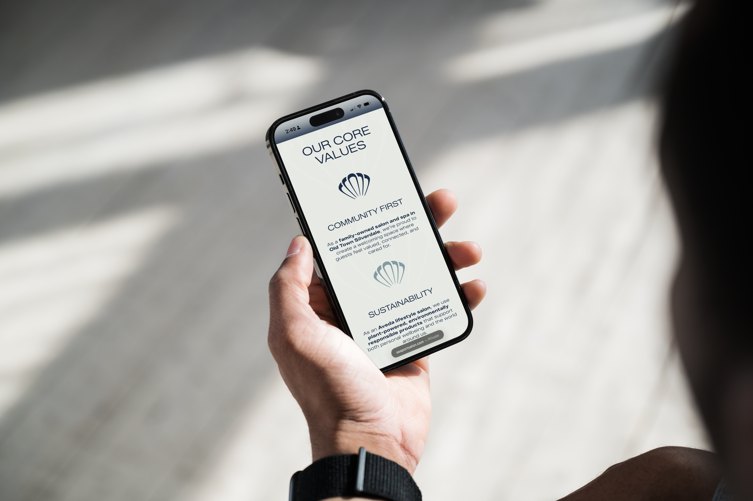 Person holding smartphone displaying company's core values on screen, with a blurred light-colored background.