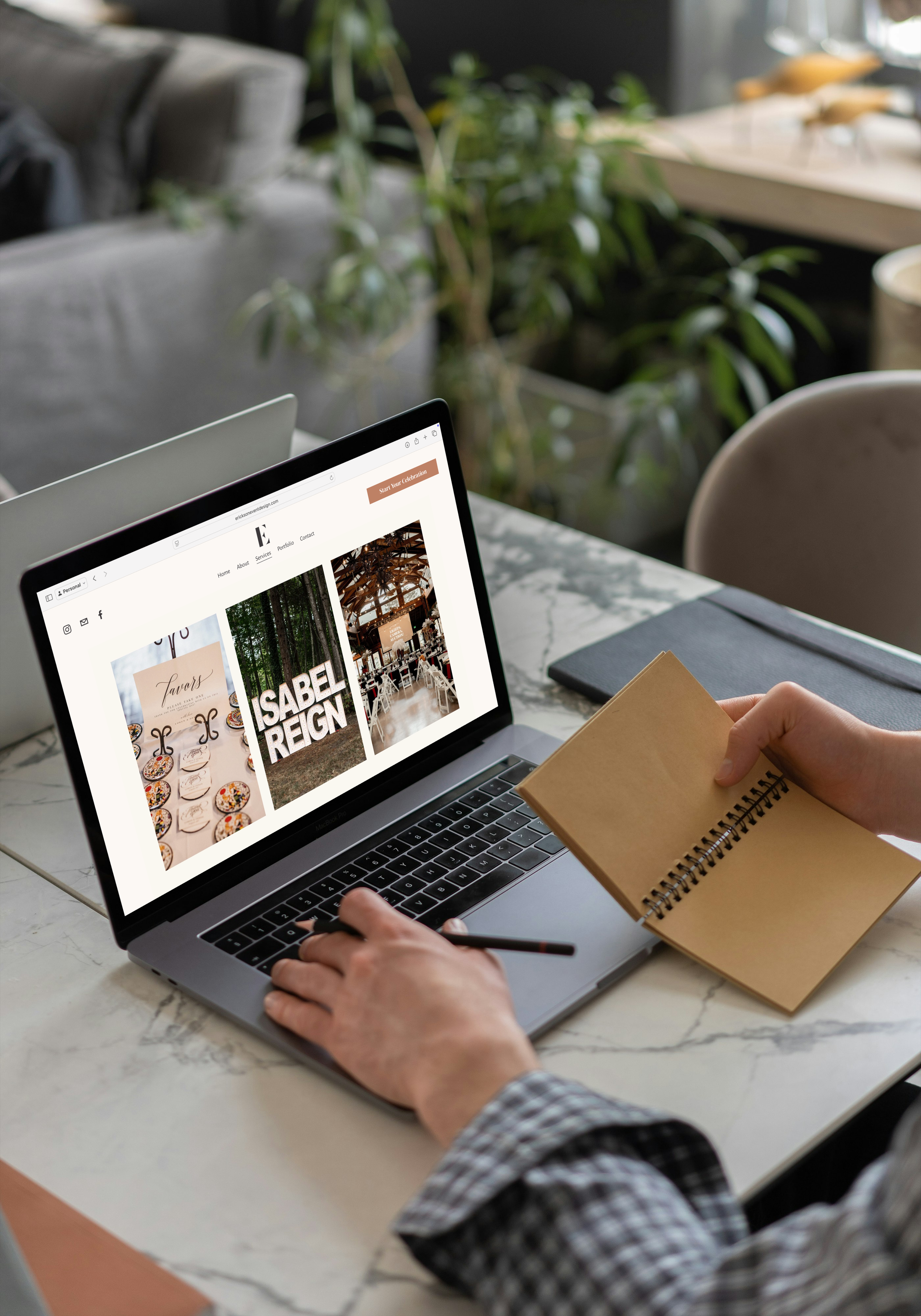 Person working on a laptop at a marble table, browsing a website related to events or venues, with a notebook in hand.