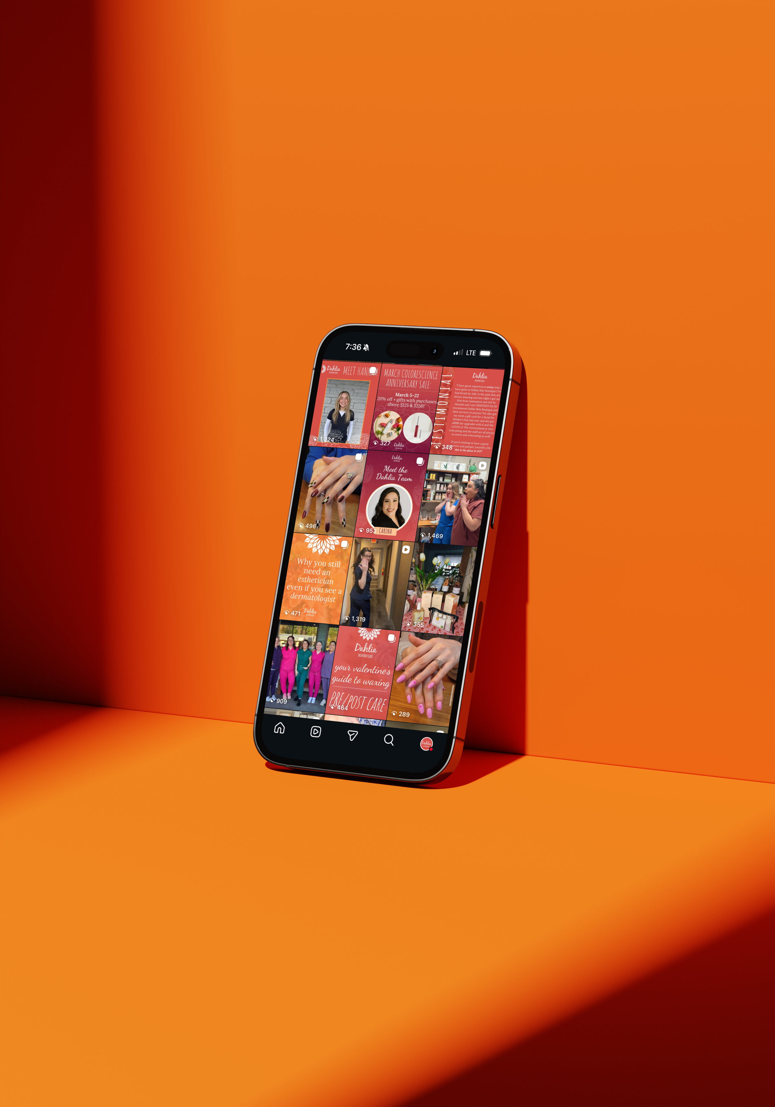 A smartphone leaning against an orange wall displays a social media platform with multiple posts related to beauty and skincare, including images of women with manicured nails and promotional content.