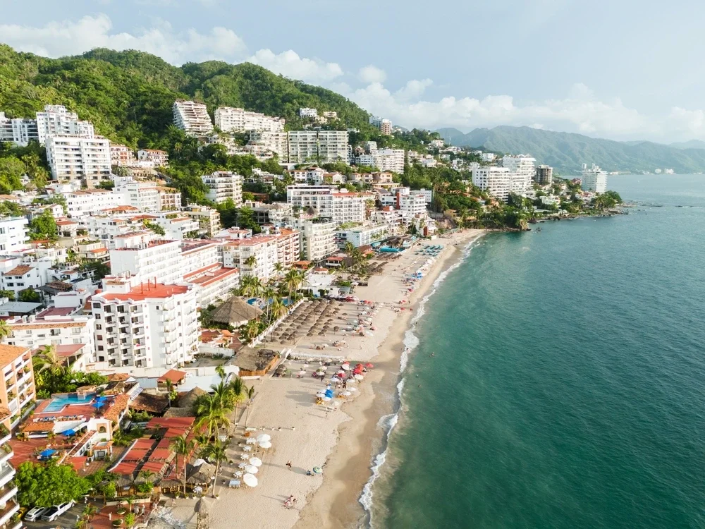 Aerial view of Puerto Vallarta bay at golden hour, mountains meeting the Pacific coastline