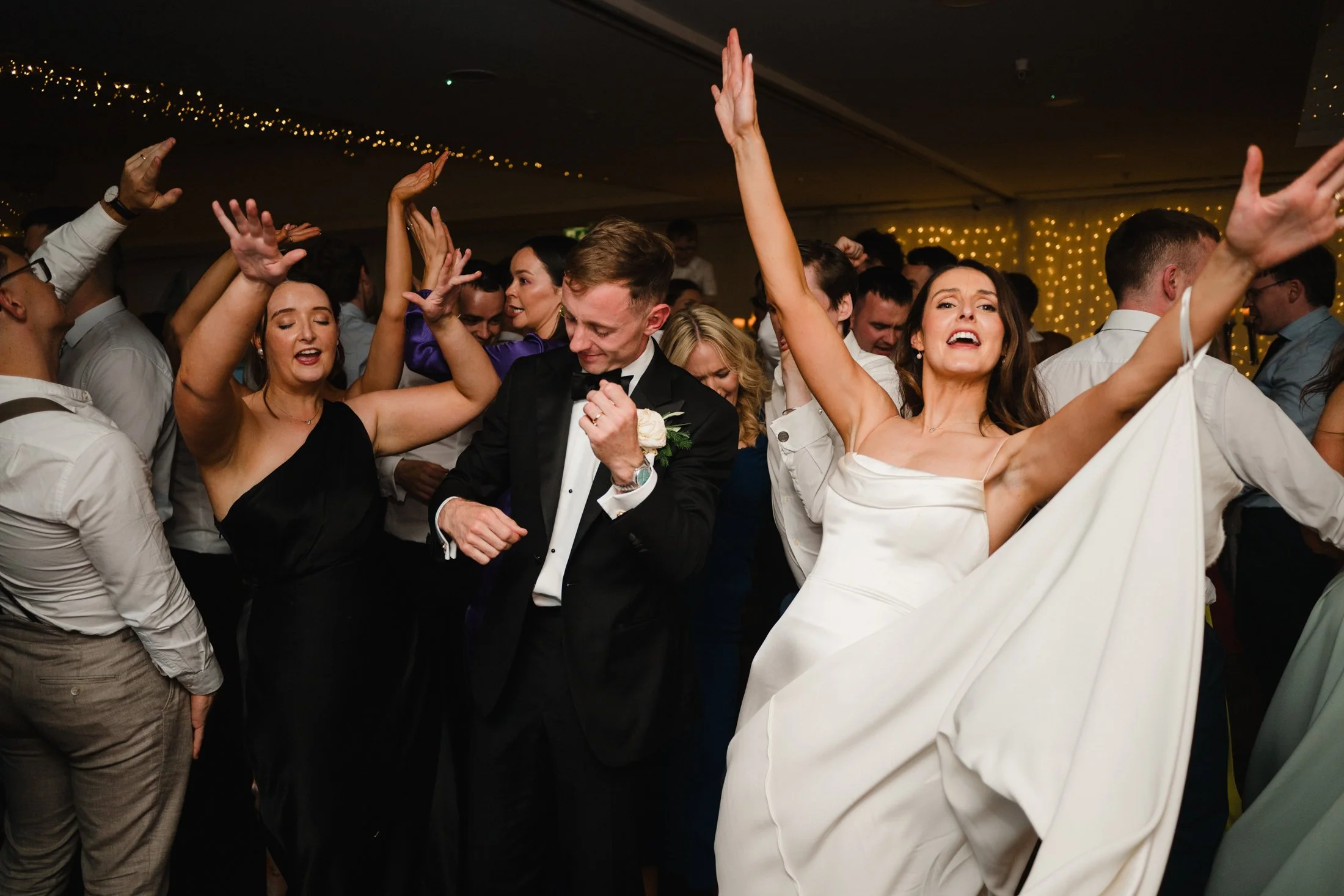 People dancing and enjoying themselves at a celebration or party celebrating at lough eske castle Co Donegal, with festive lighting and decorations in the background.