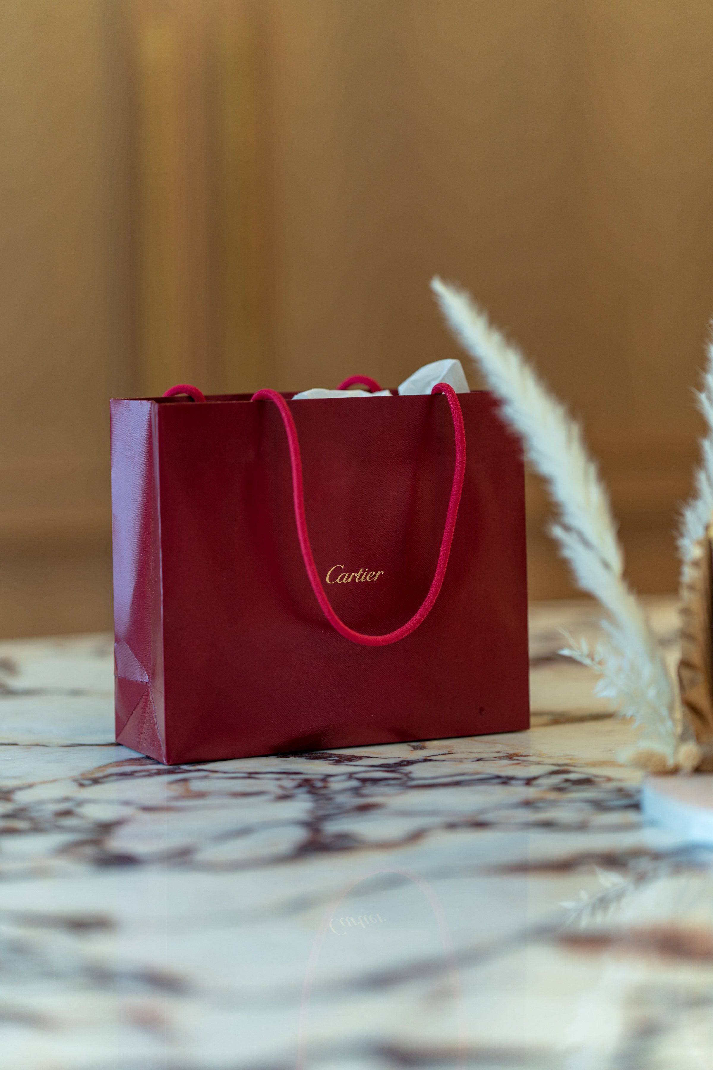 Red Cartier shopping bag with handles on a marble surface