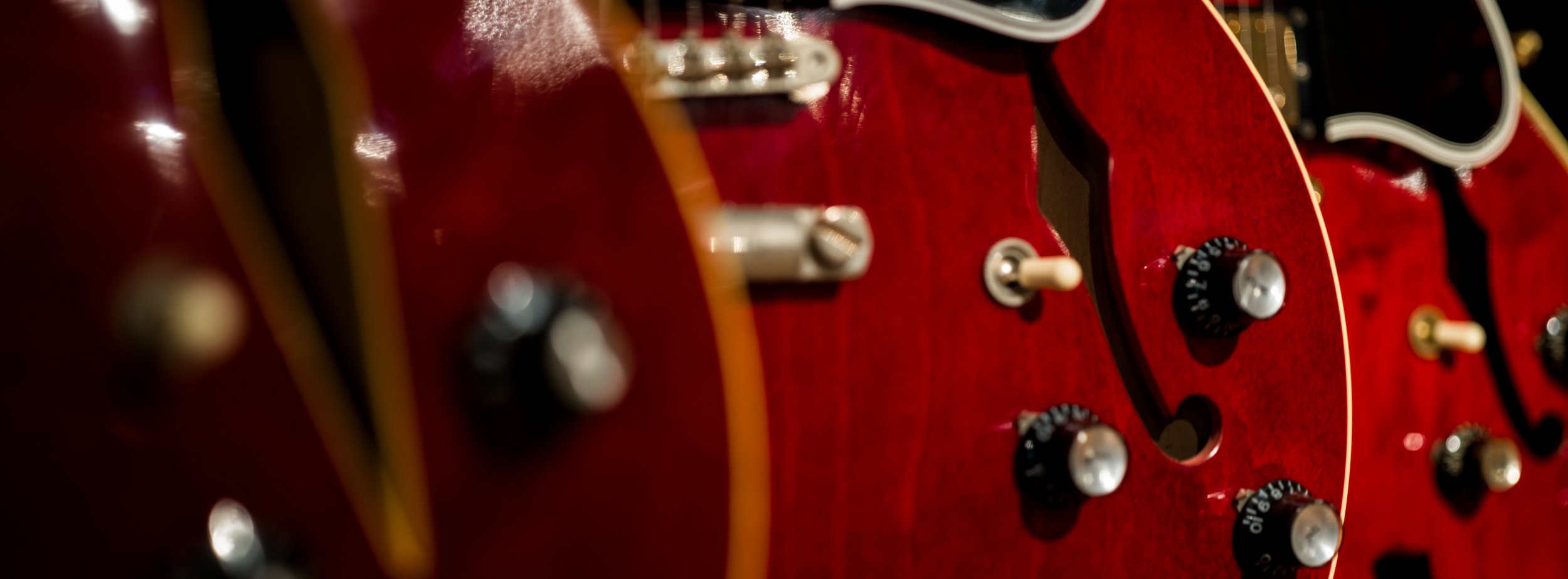 Close up of three red hollow-body guitars