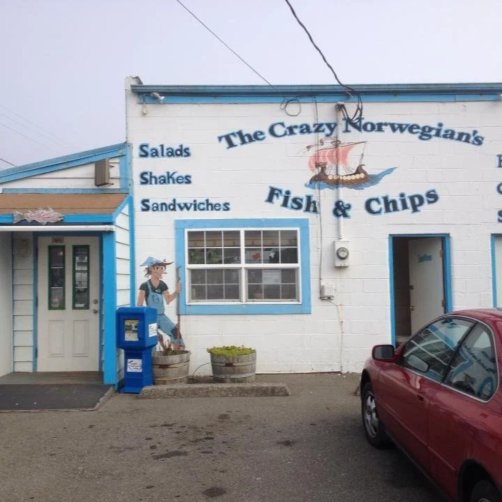 A picture showing the entrance to The Crazy Norwegian's Fish & Chips restaurant, with parking in front.