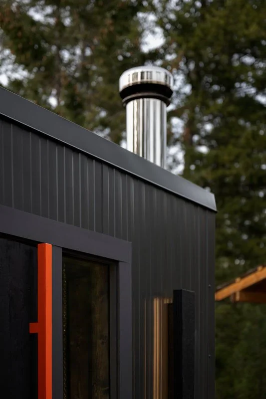 Pihka sauna metal cladding, stainless chimney and orange door handle detail