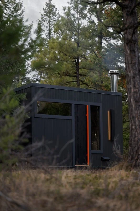 Black Pihka sauna with stainless chimney in a pine forest