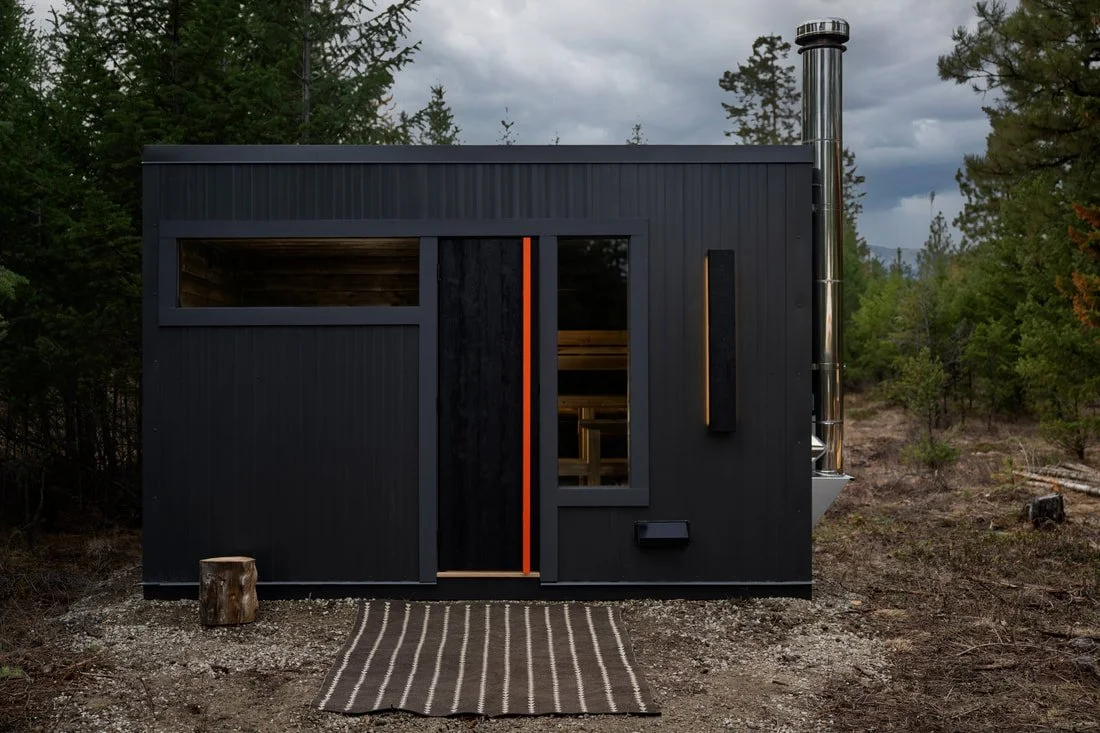 Black Pihka sauna with orange door handle and transom window