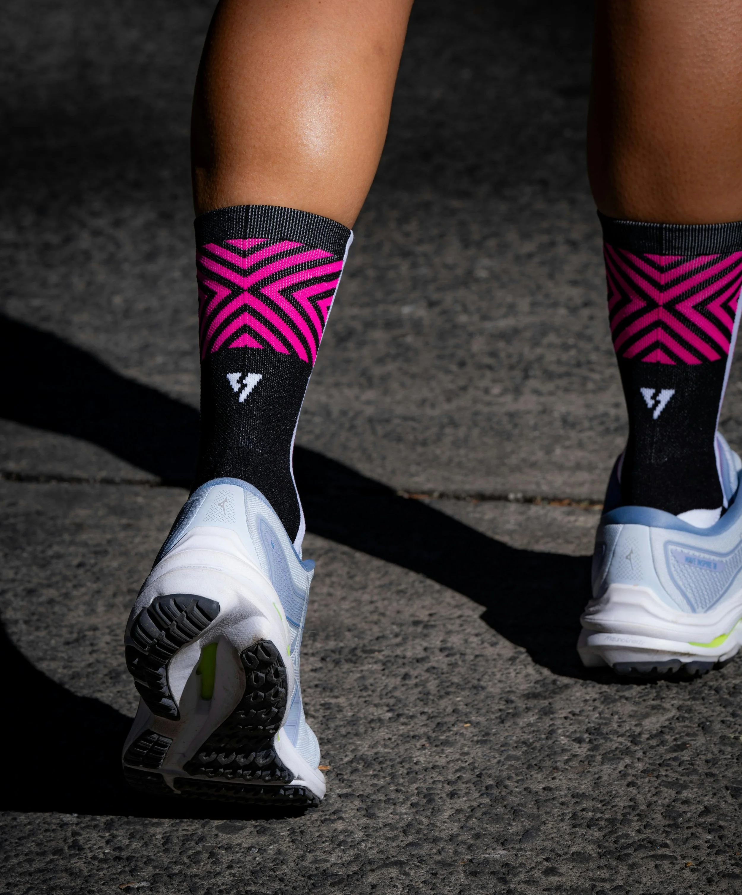 A woman wearing a black sports bra and black shorts jogging outdoors during daytime.
