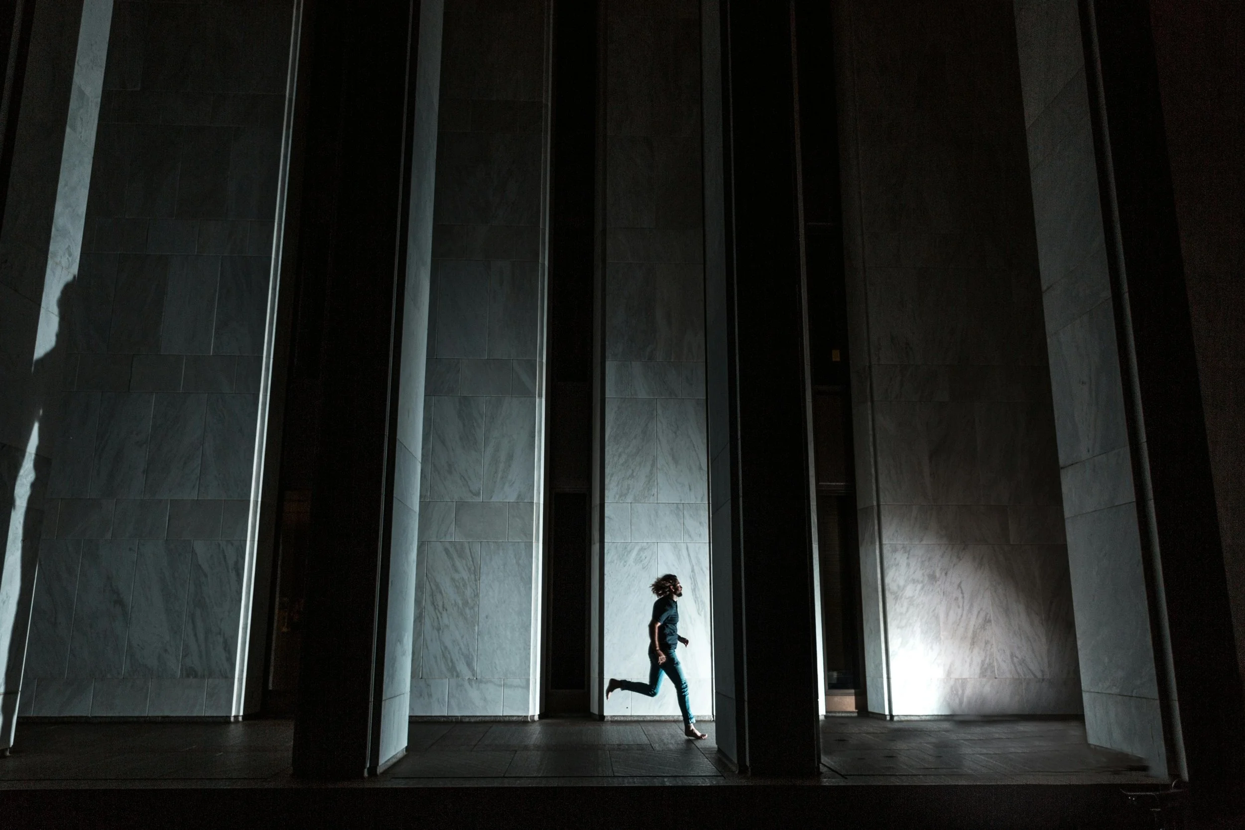 Scenic landscape of rolling green meadows with a narrow dirt path leading toward distant mountains, under a sky with wispy clouds at sunset.