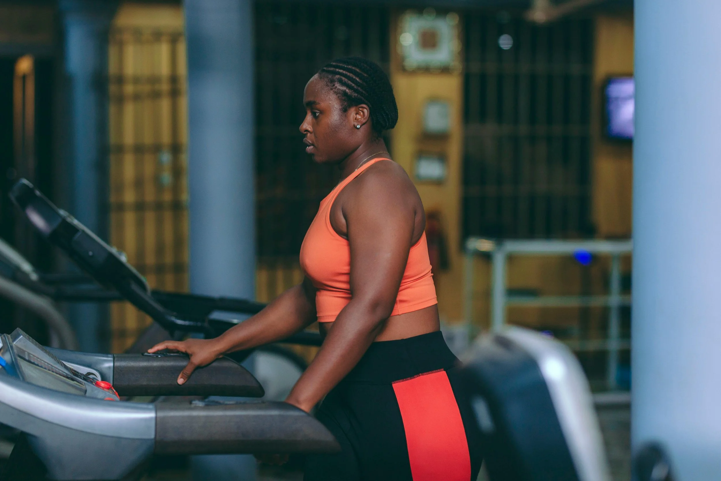 A woman in workout clothes stretching against a plain white wall.