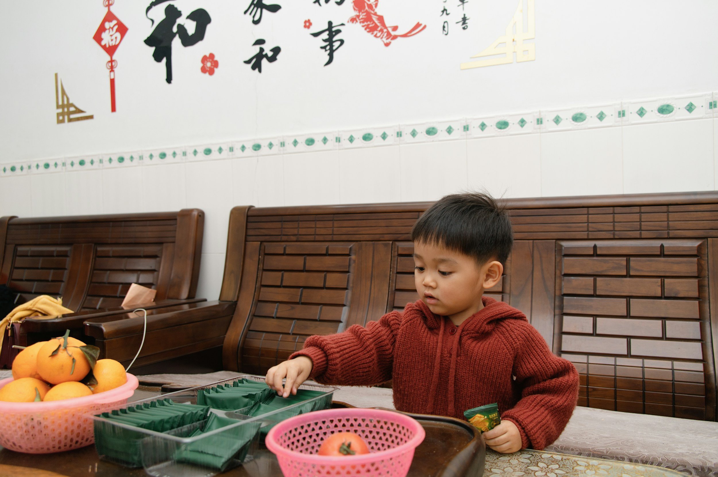 Young child seated at a table reaching towards bowls of fresh food