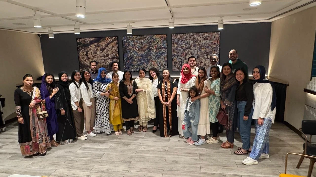Group of diverse people posing for a photo in an indoor setting with modern decor and artwork in the background.