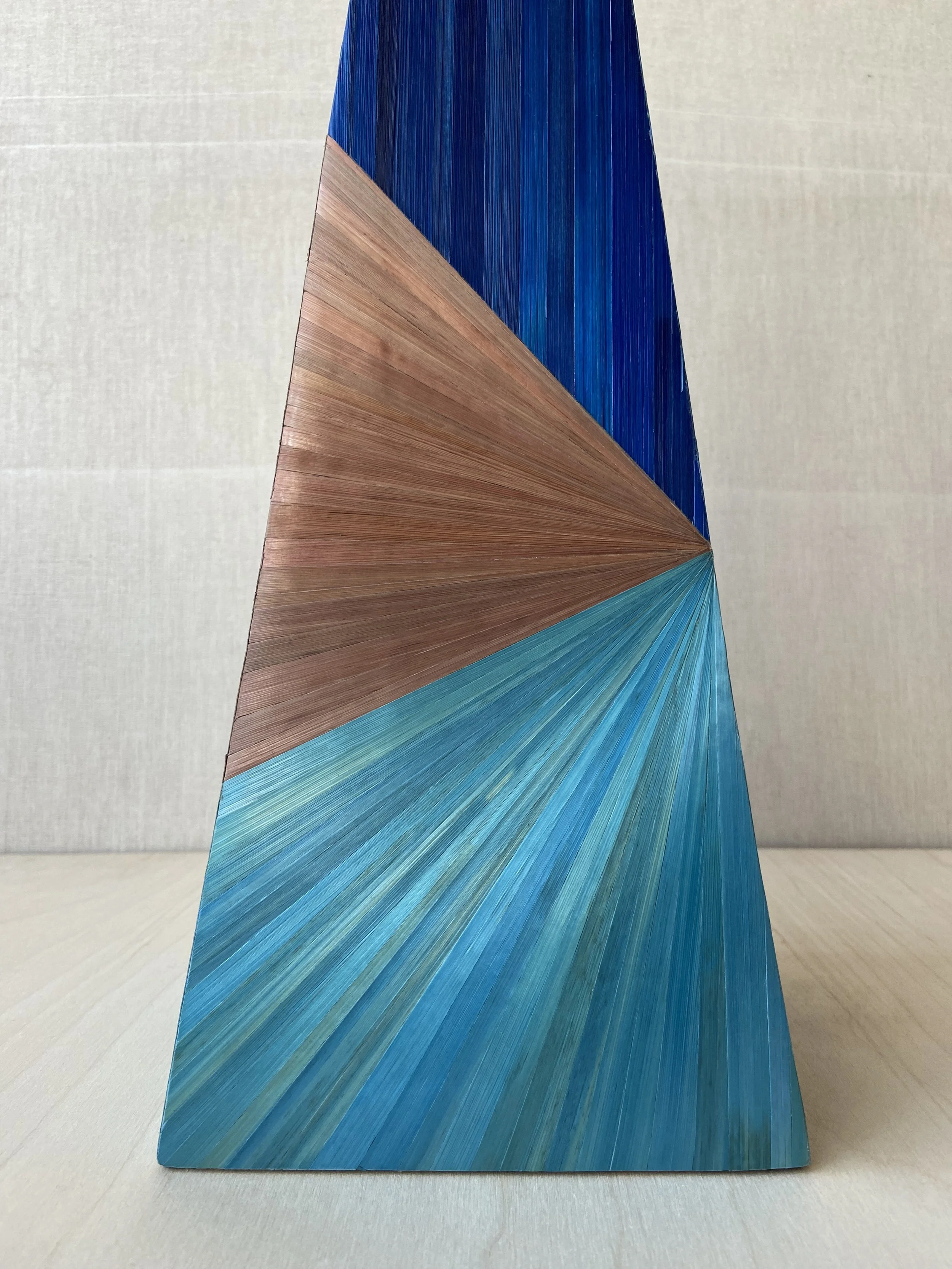 Close-up of Eleanor Nadimi's Prism pyramid lamp base, showing geometric blue, turquoise and brown straw marquetry.