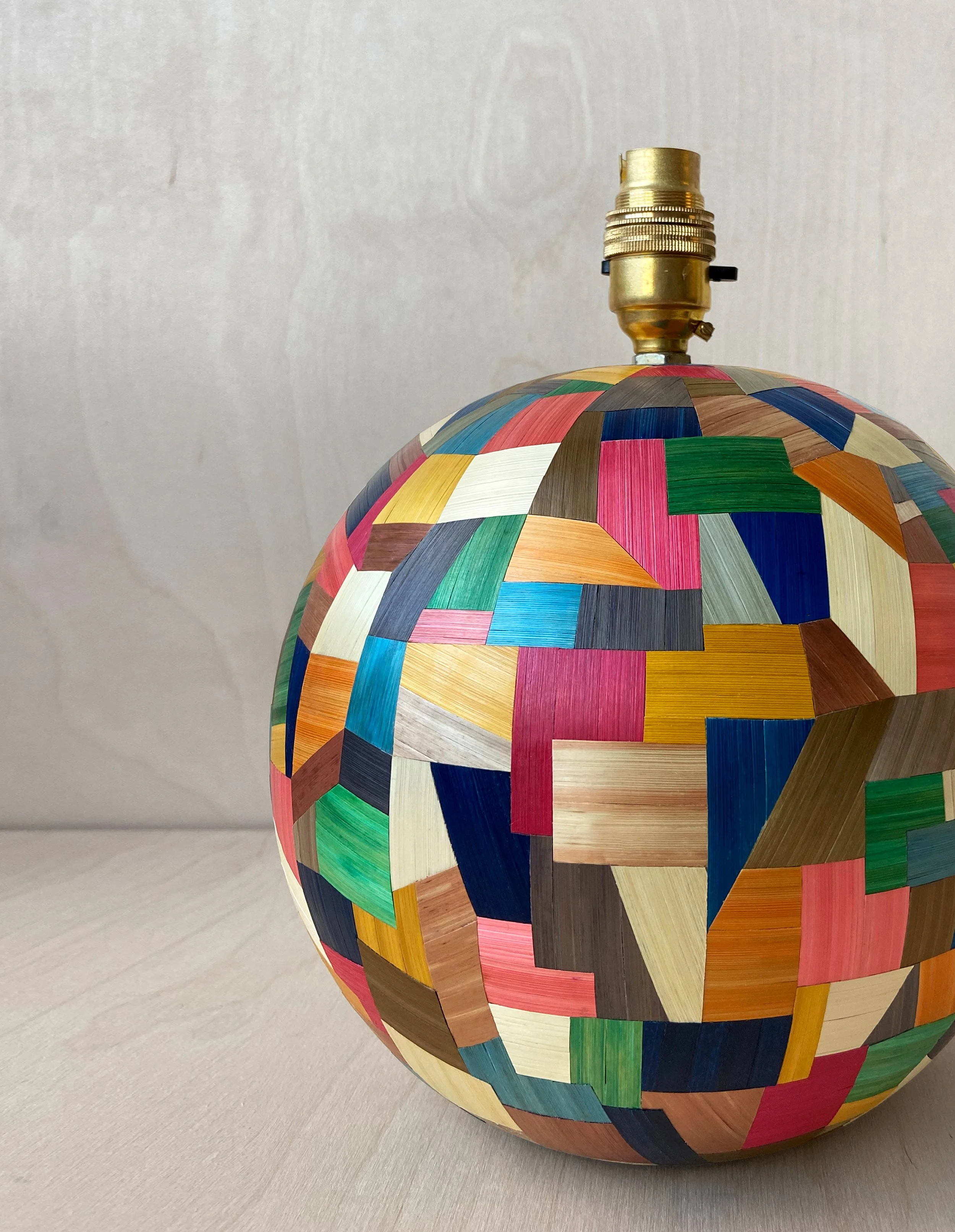 Close-up of Eleanor Nadimi's Confetti sphere lamp base, showing individually cut pieces of colourful straw arranged in an intricate geometric patchwork.