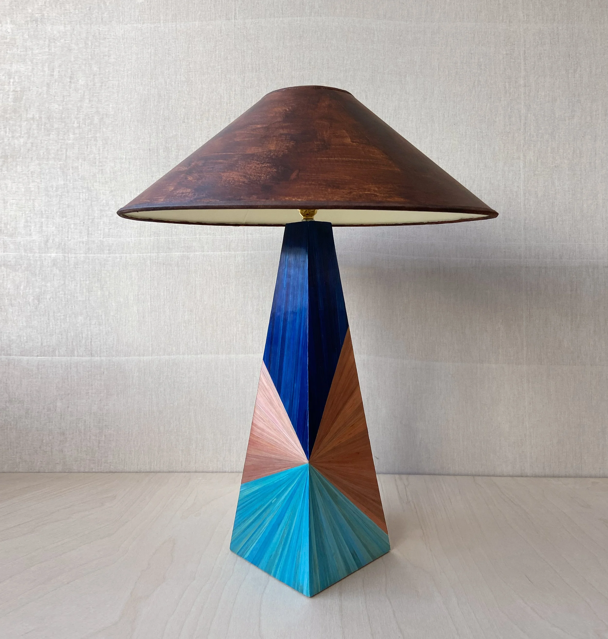 Prism pyramid table lamp base by Eleanor Nadimi, featuring hand-cut blue, turquoise and brown straw marquetry in a geometric design.