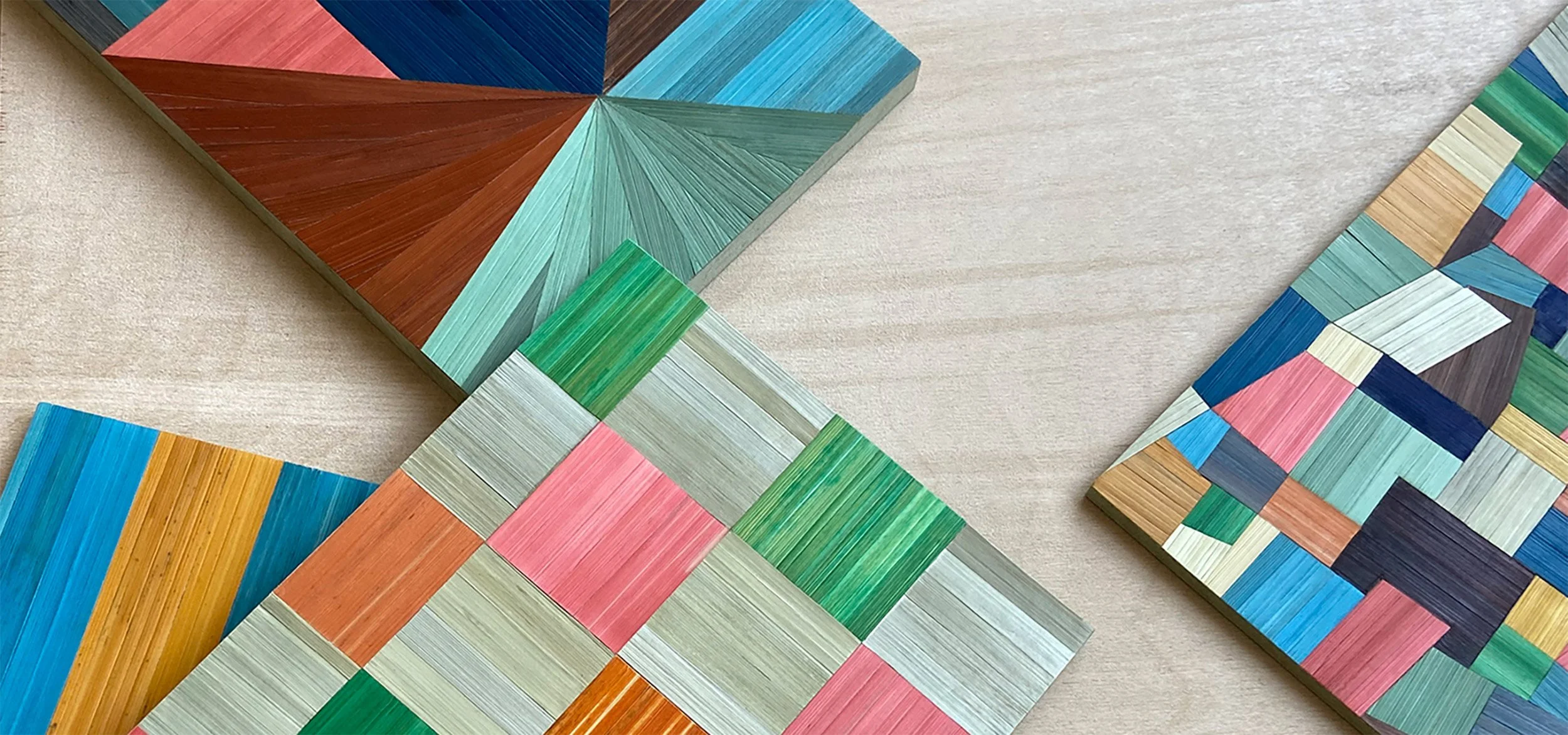 Collection of colourful straw-marquetry samples handmade by Eleanor Nadimi using dyed rye straw in geometric compositions.