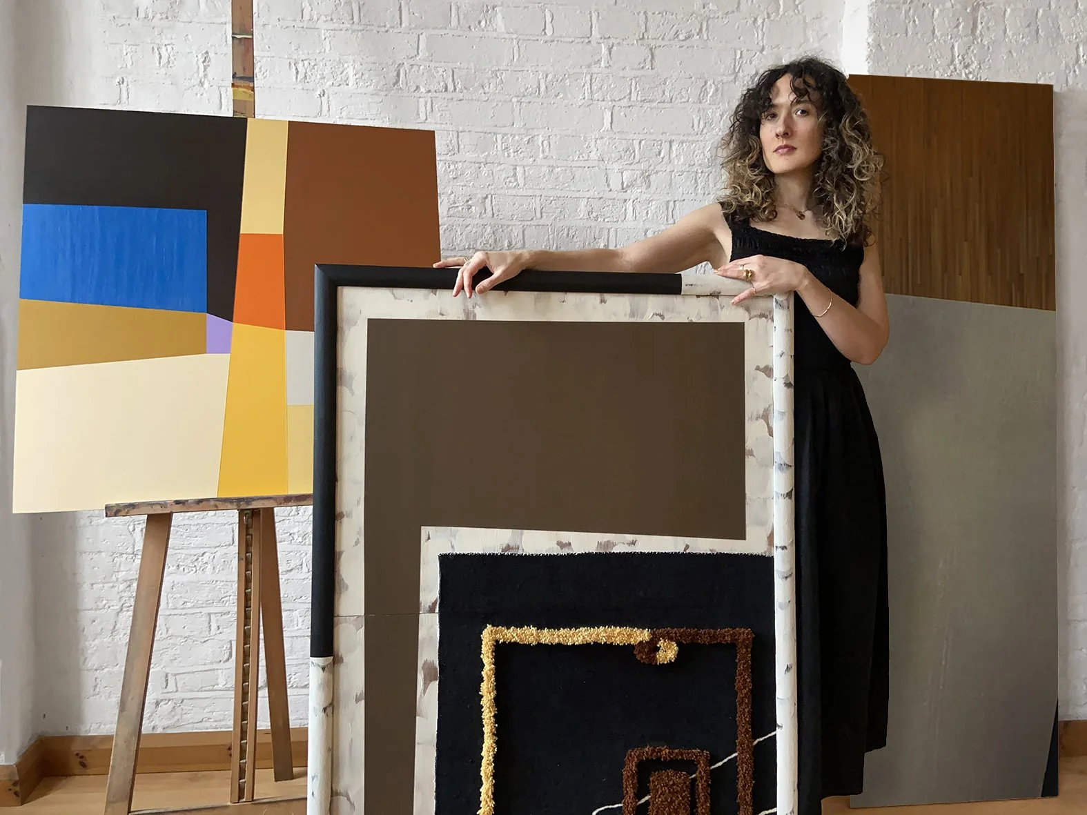 London artist and designer Eleanor Nadimi in her studio with an abstract painting and a hand-tufted textile artwork.