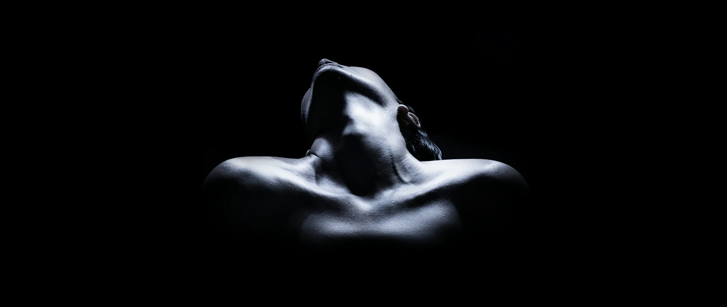 A black and white photograph of a person's upper body and face, with the head tilted back and eyes closed, relaxed and embodied after sex therapy.