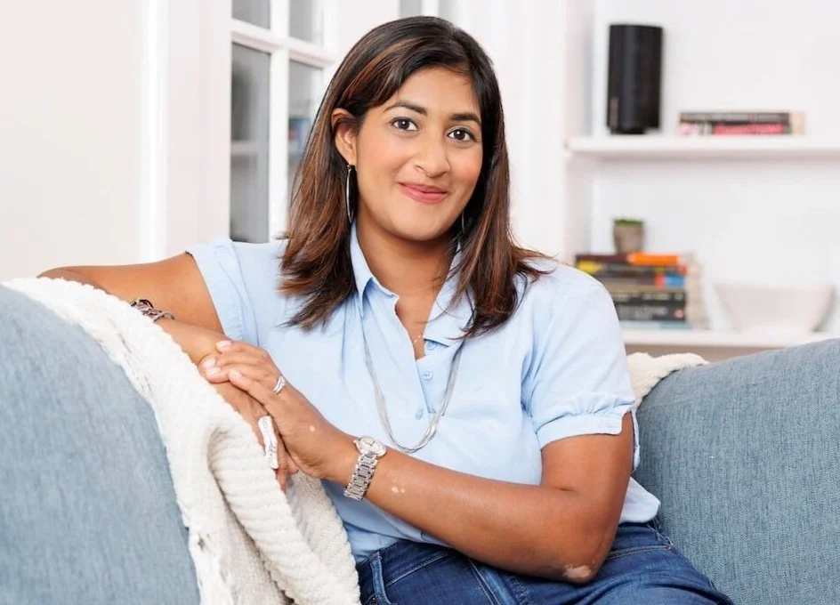 Psychotherapy supervisor Dr. Sumi smiling, sitting on a couch with books in background