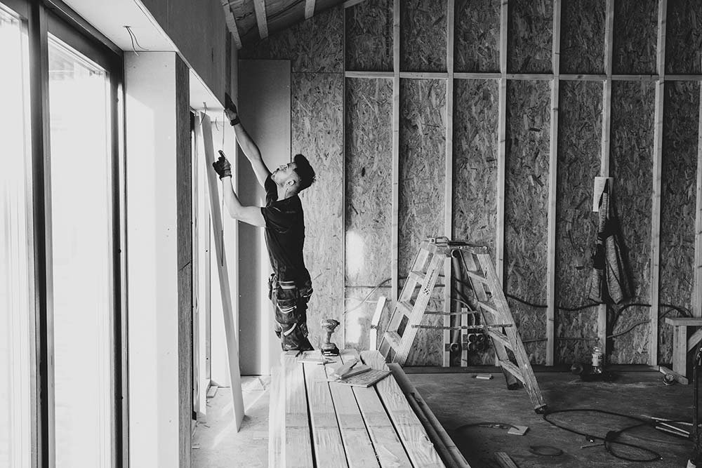 A construction worker putting up drywall in a new home addition, showcasing the renovation process.