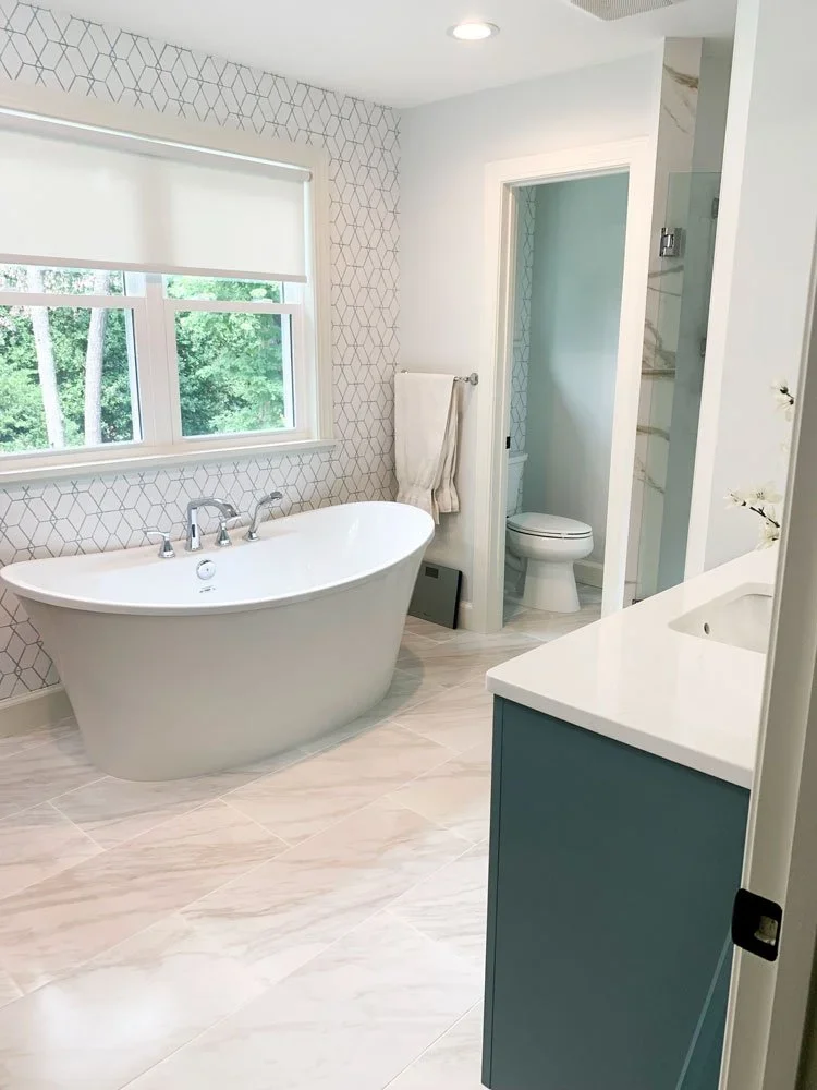 A spacious bathroom remodel with marbled floor, light walls, and a large, standalone white bathtub.