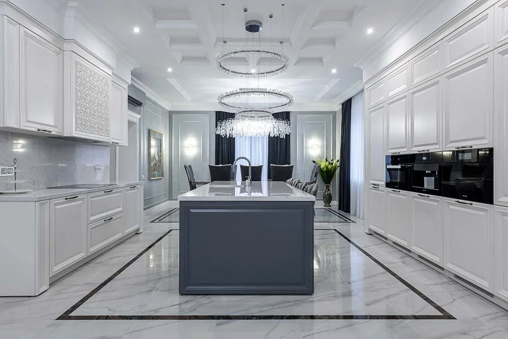 Luxury kitchen featuring marble flooring, chandelier, and a minimalist, clean white design.
