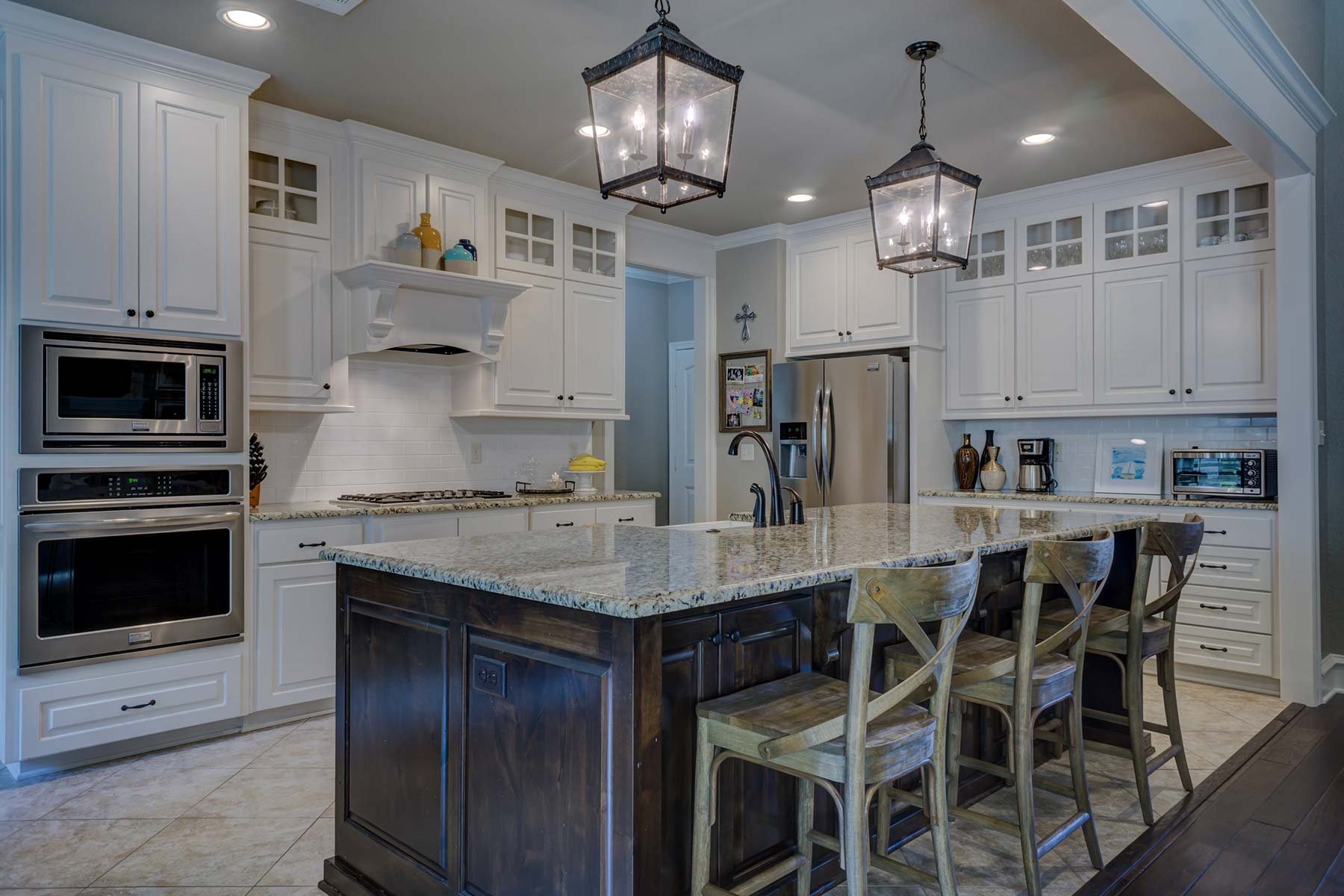 A remodeled kitchen in Mooresville with marble counters, traditional lighting, and custom cabinets.