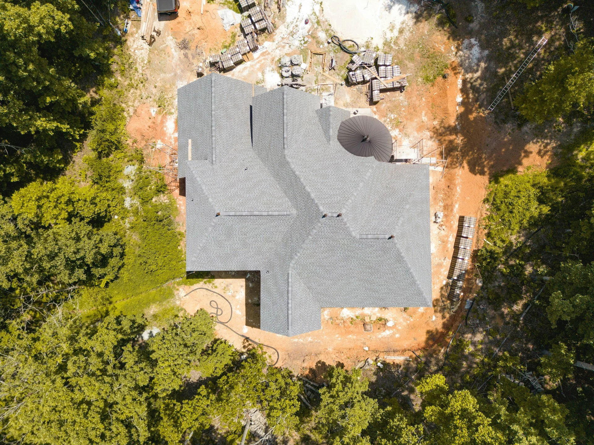 An aerial view of a new custom home under construction on a wooded lot in North Carolina.