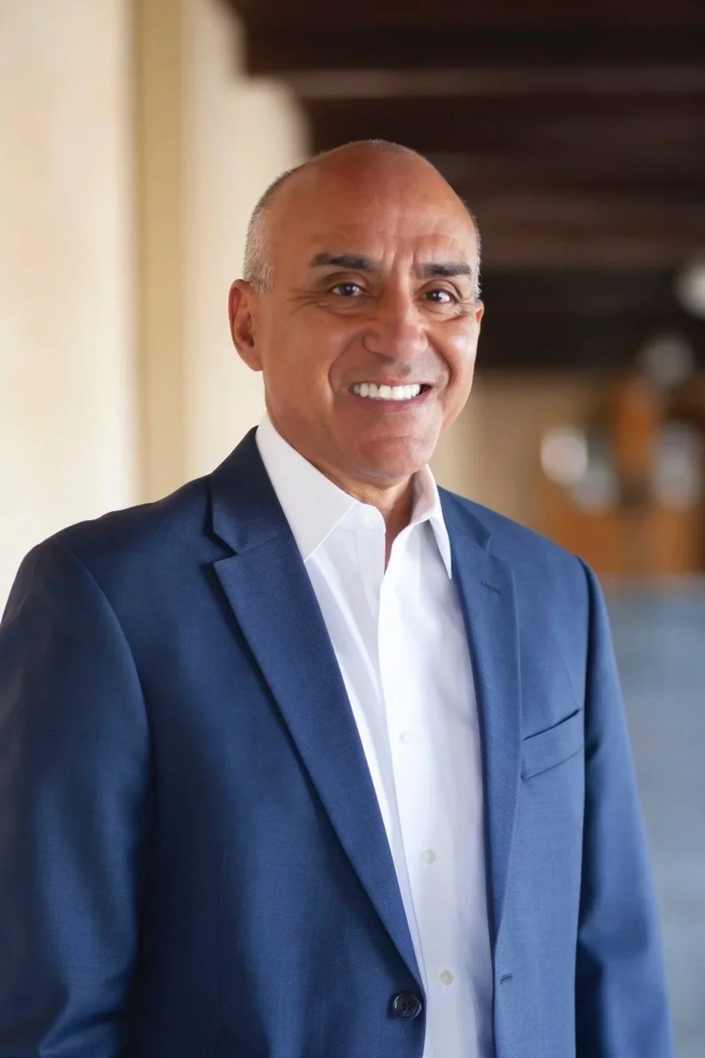 A man with a shaved head wearing blue suit.