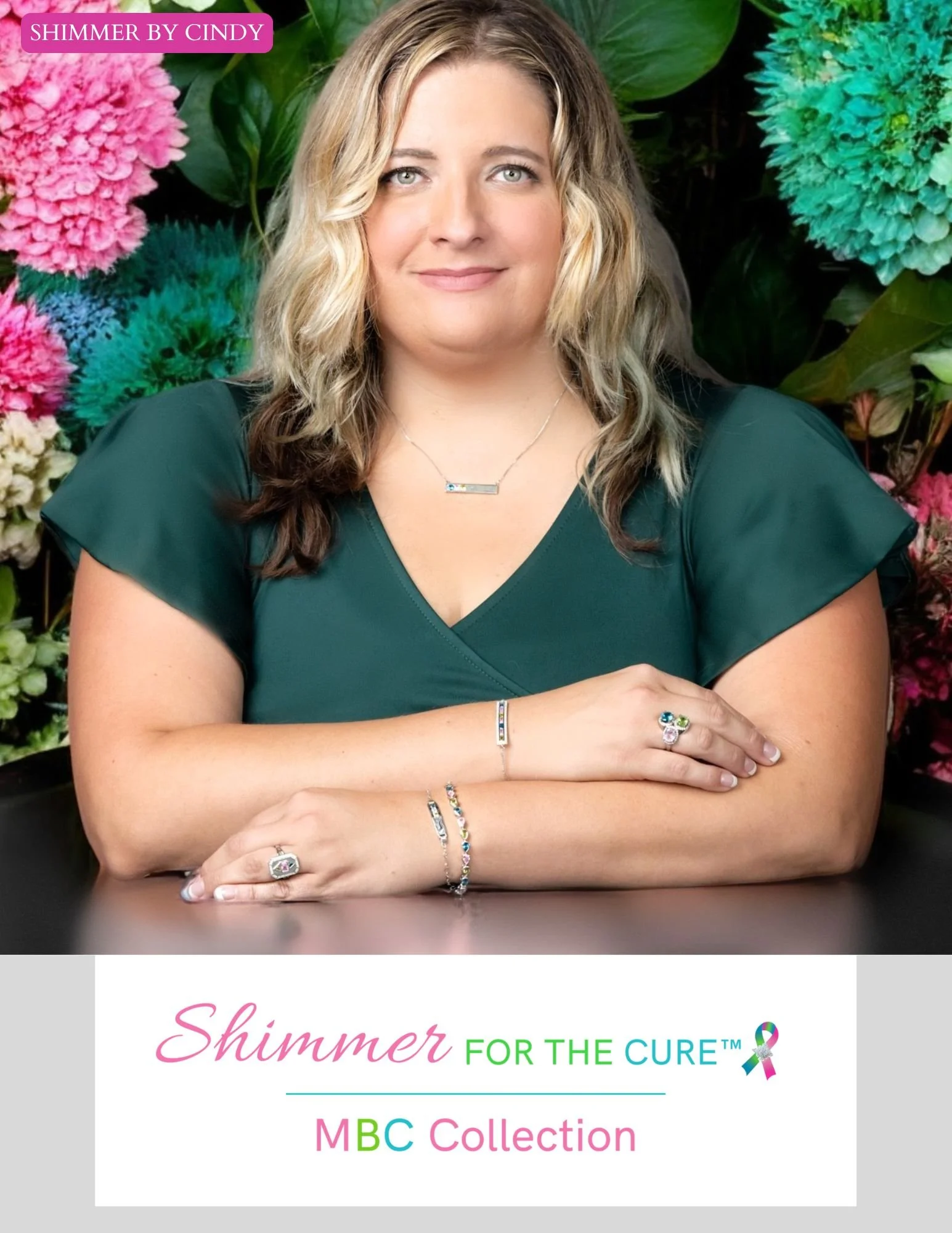 Woman with wavy blonde hair wearing a green top, sitting at a table with hands folded, showcasing jewelry. Text says "Shimmer by Cindy" and "Shimmer for the Cure MBC Collection."