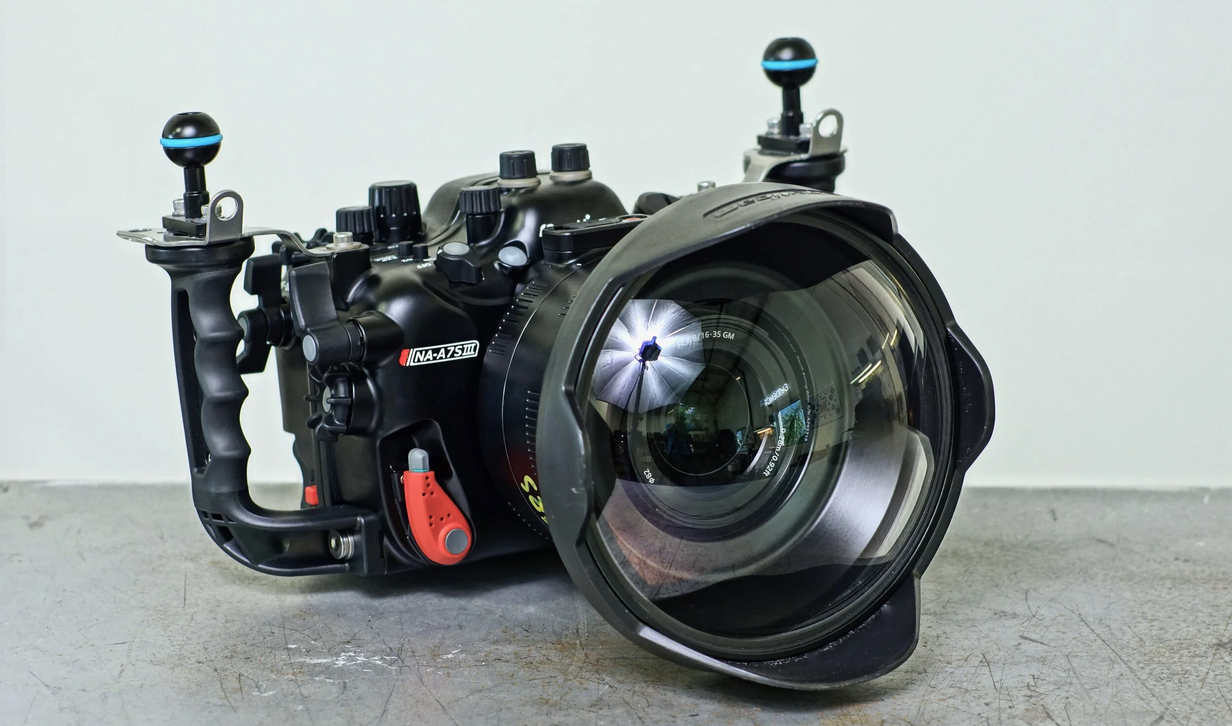 Underwater camera with large lens and control buttons, placed on a concrete surface.